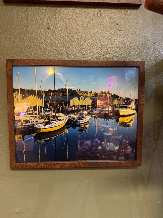 A beautifully composed 11×14 framed photograph capturing a peaceful marina filled with sailboats, reflections, and warm evening light. The natural wood-toned frame adds warmth and makes this piece easy to style in coastal, nautical, or Pacific Northwest-inspired spaces.
