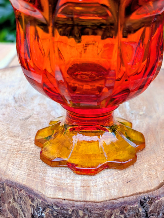 Bring a warm glow to your home with this vintage Fenton Valencia covered glass jar in vibrant Orange Amberina. Originally marketed as a cigarette box, this versatile Mid-Century piece now shines as a candy dish, apothecary jar, or decorative accent with timeless vintage appeal.