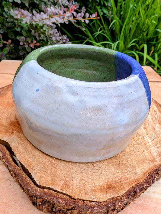 A beautifully hand-thrown studio pottery succulent planter featuring layered blue, moss green, and soft white glazes over high-fired stoneware. Complete with an integrated drainage hole and signed by the artist with the monogram "G.M.," this artisan planter brings handcrafted character to any home or garden.