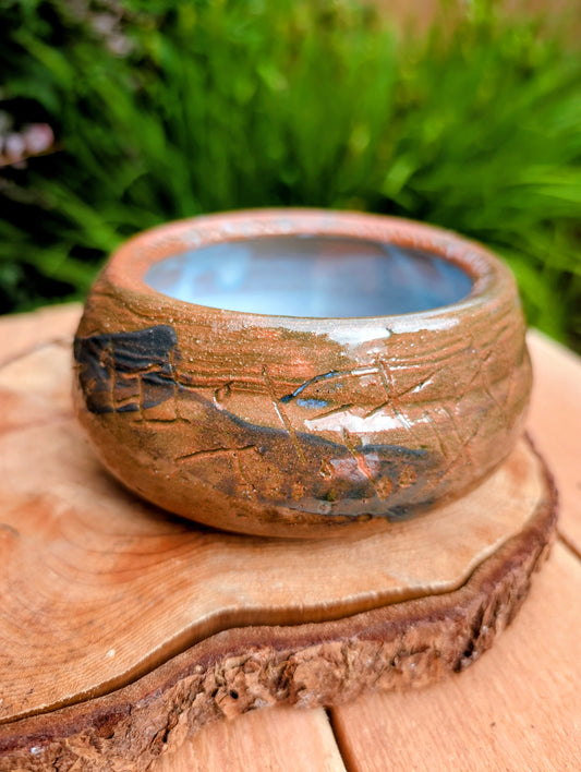 Handcrafted with richly carved texture and a soft blue reactive glaze, this signed studio pottery bowl brings warmth and character to any home. Ideal as a serving bowl, decorative accent, or functional piece of everyday artisan pottery.