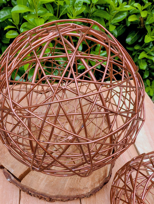 Bring warmth and texture to your home with this coordinated set of two copper-tone woven metal decorative spheres. Their sculptural open-weave design complements modern organic, farmhouse, industrial, and contemporary interiors, making them versatile accents for shelves, coffee tables, decorative bowls, and centerpieces.