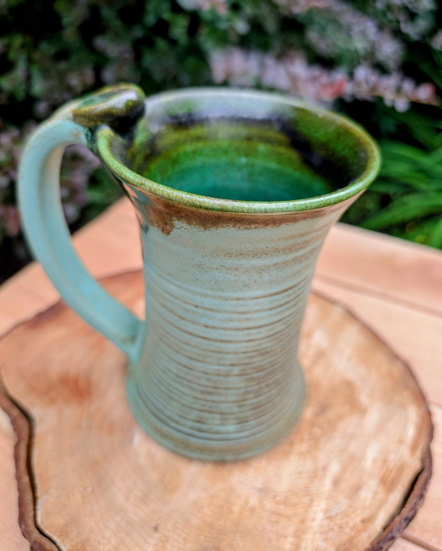 A beautifully handcrafted studio pottery tankard-style mug, wheel-thrown in Hot Springs, Arkansas and dated 2007. Its flowing turquoise, olive, and bronze glaze, generous size, and comfortable thumb-rest handle make it both a functional everyday piece and a collectible example of American studio pottery.