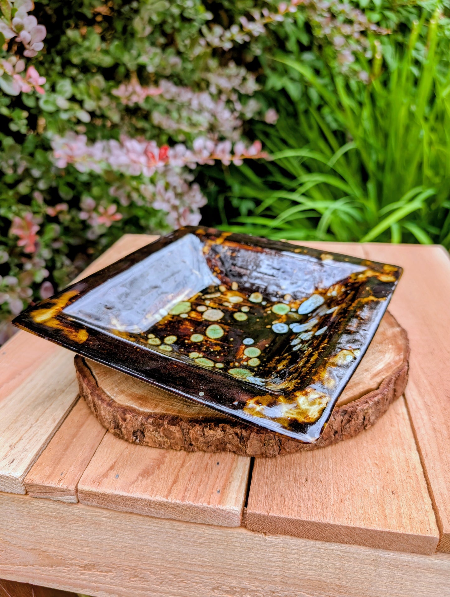 Bring handcrafted artistry into your home with this one-of-a-kind square studio pottery dish. Its rich chocolate brown glaze is accented by constellation-like blue, green, and cream crystalline details, making it equally beautiful as a decorative catchall, appetizer dish, or display piece.