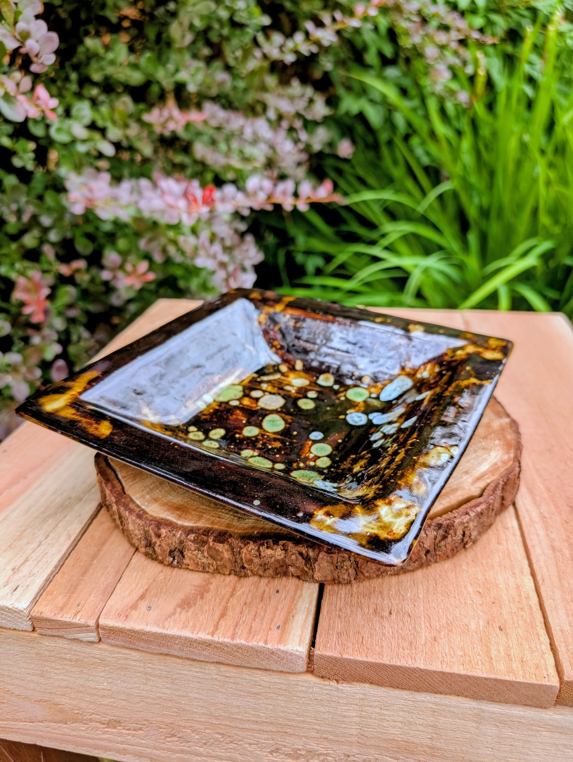Bring handcrafted artistry into your home with this one-of-a-kind square studio pottery dish. Its rich chocolate brown glaze is accented by constellation-like blue, green, and cream crystalline details, making it equally beautiful as a decorative catchall, appetizer dish, or display piece.