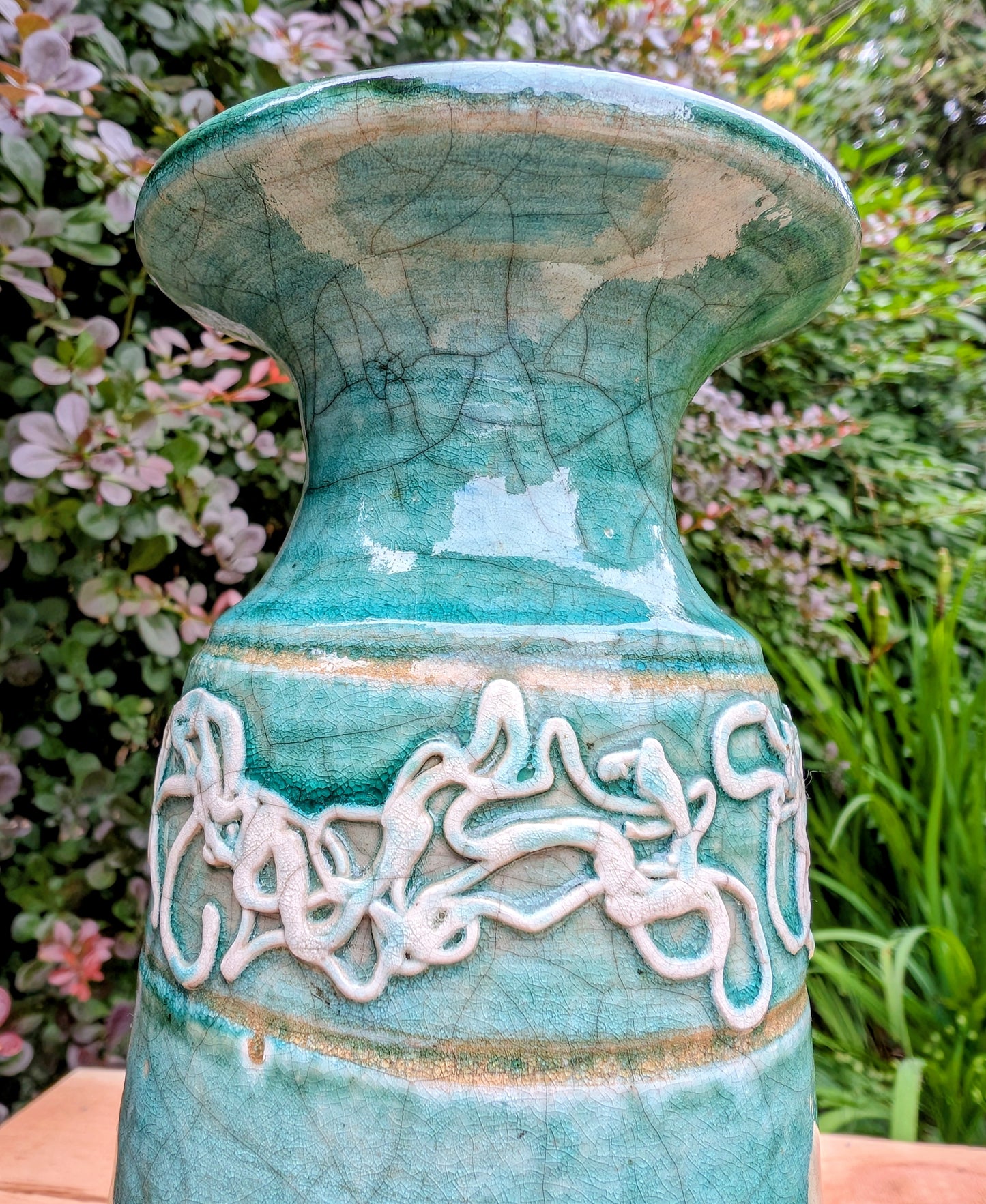 Celebrate the artistry of 1970s studio ceramics with this signed and dated handmade stoneware vase. Finished in a rich teal crackle glaze with distinctive white applied slip decoration, this sculptural piece brings timeless character to shelves, tables, and curated collections.