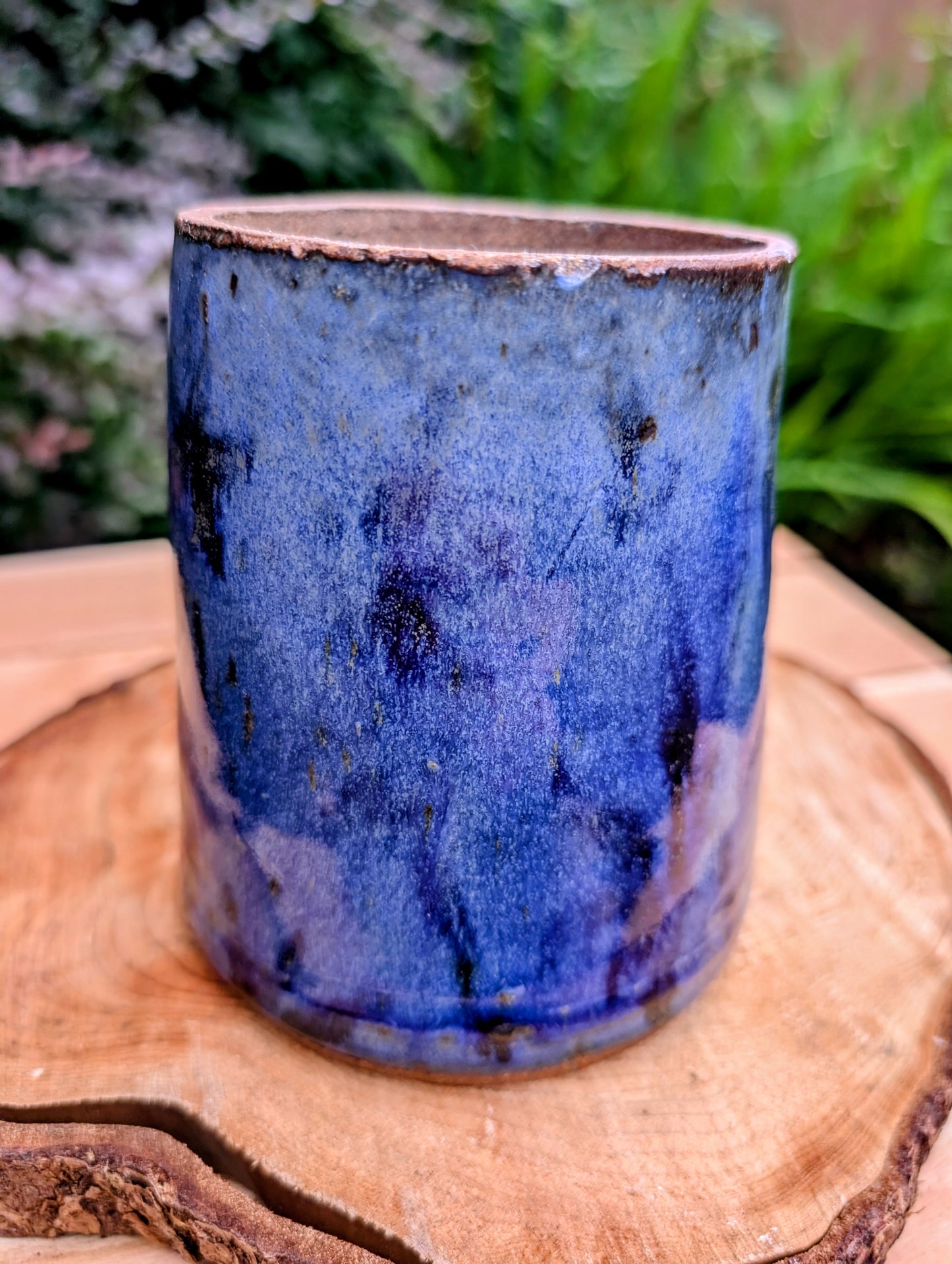 Hand-thrown and artist signed, this versatile stoneware vessel features a rich variegated cobalt blue glaze with an exposed stoneware rim that highlights its handcrafted character. Beautiful as a vase, utensil crock, brush holder, or decorative accent, it brings timeless studio craftsmanship to any home.