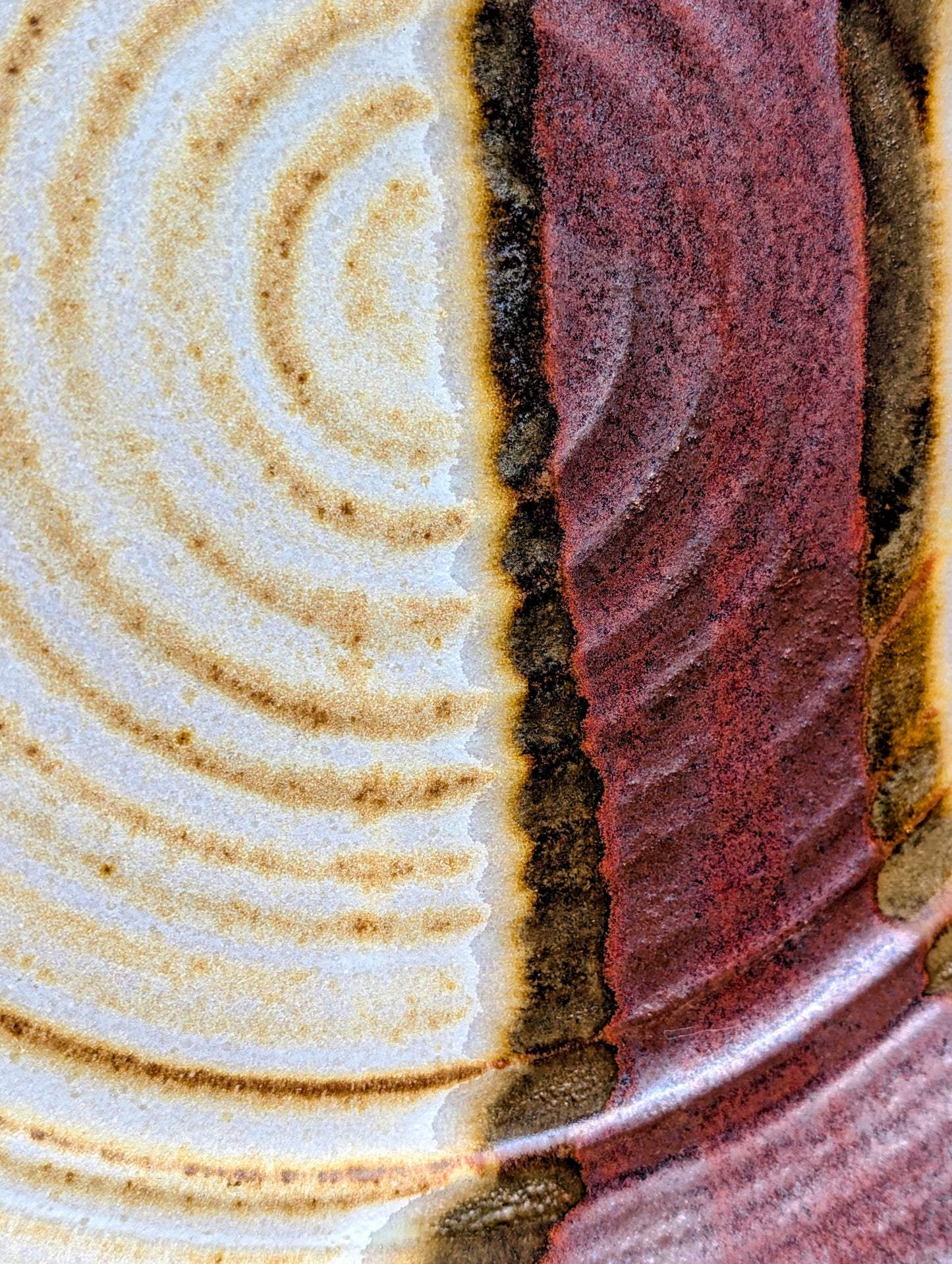 A striking hand-thrown studio pottery platter featuring an expressive cream, maroon, and olive glaze composition with visible throwing rings and an incised artist signature. Beautiful as both a decorative wall display and a functional serving piece, it embodies the warmth and craftsmanship of contemporary American studio ceramics.