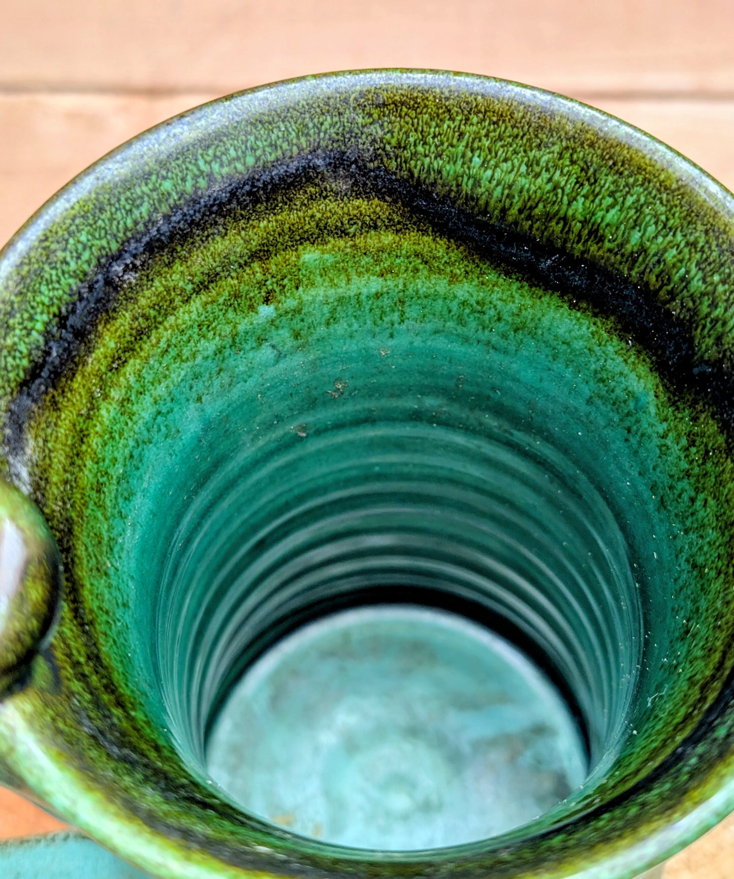 A beautifully handcrafted studio pottery tankard-style mug, wheel-thrown in Hot Springs, Arkansas and dated 2007. Its flowing turquoise, olive, and bronze glaze, generous size, and comfortable thumb-rest handle make it both a functional everyday piece and a collectible example of American studio pottery.