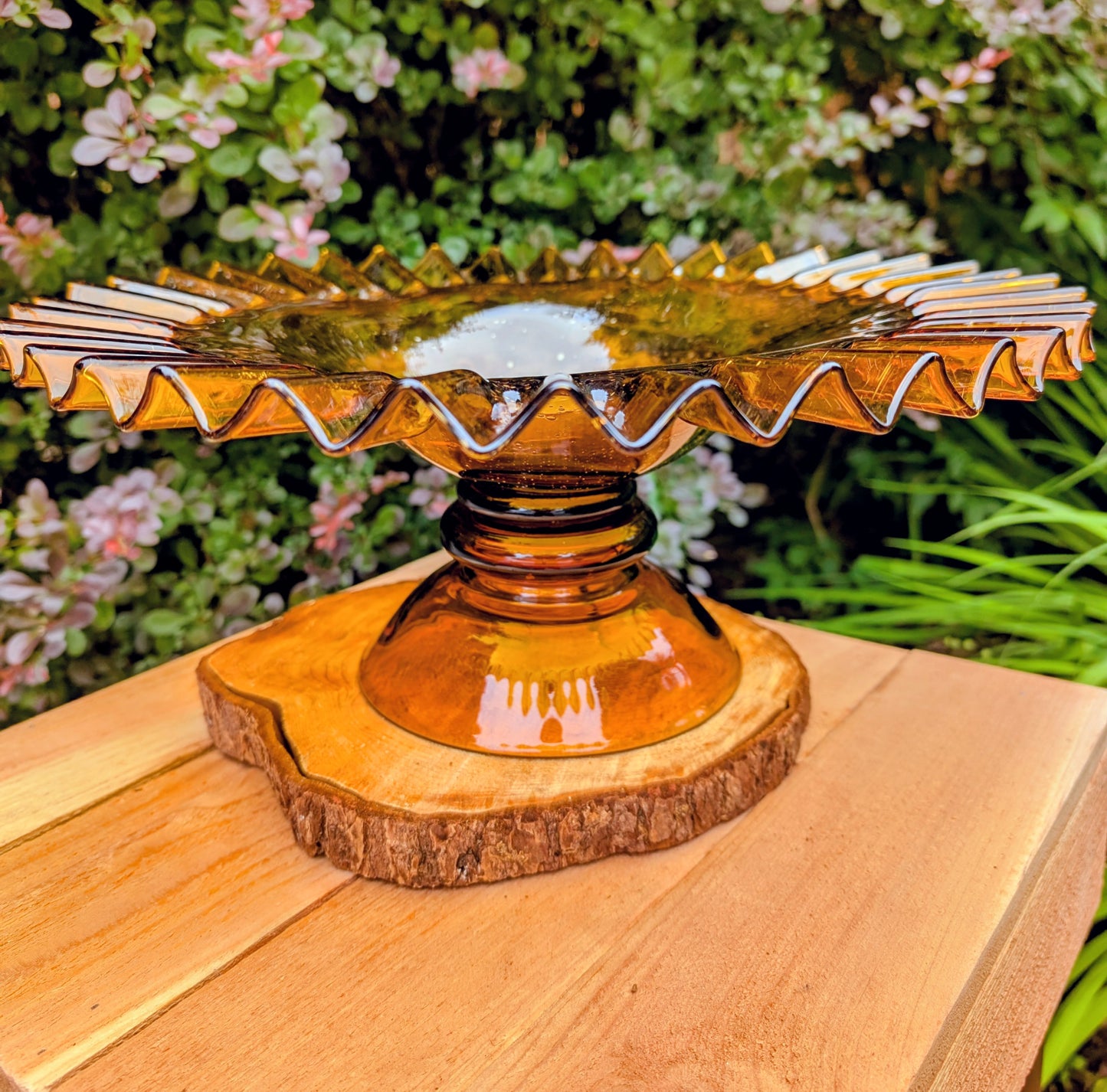 Bring warm vintage charm to your home with this large amber pressed glass pedestal console bowl, estimated to have been made by Indiana Glass during the 1960s–1970s. Its dramatic ruffled rim and generous size make it a beautiful centerpiece for seasonal displays, fruit, florals, or decorative accents throughout the year.