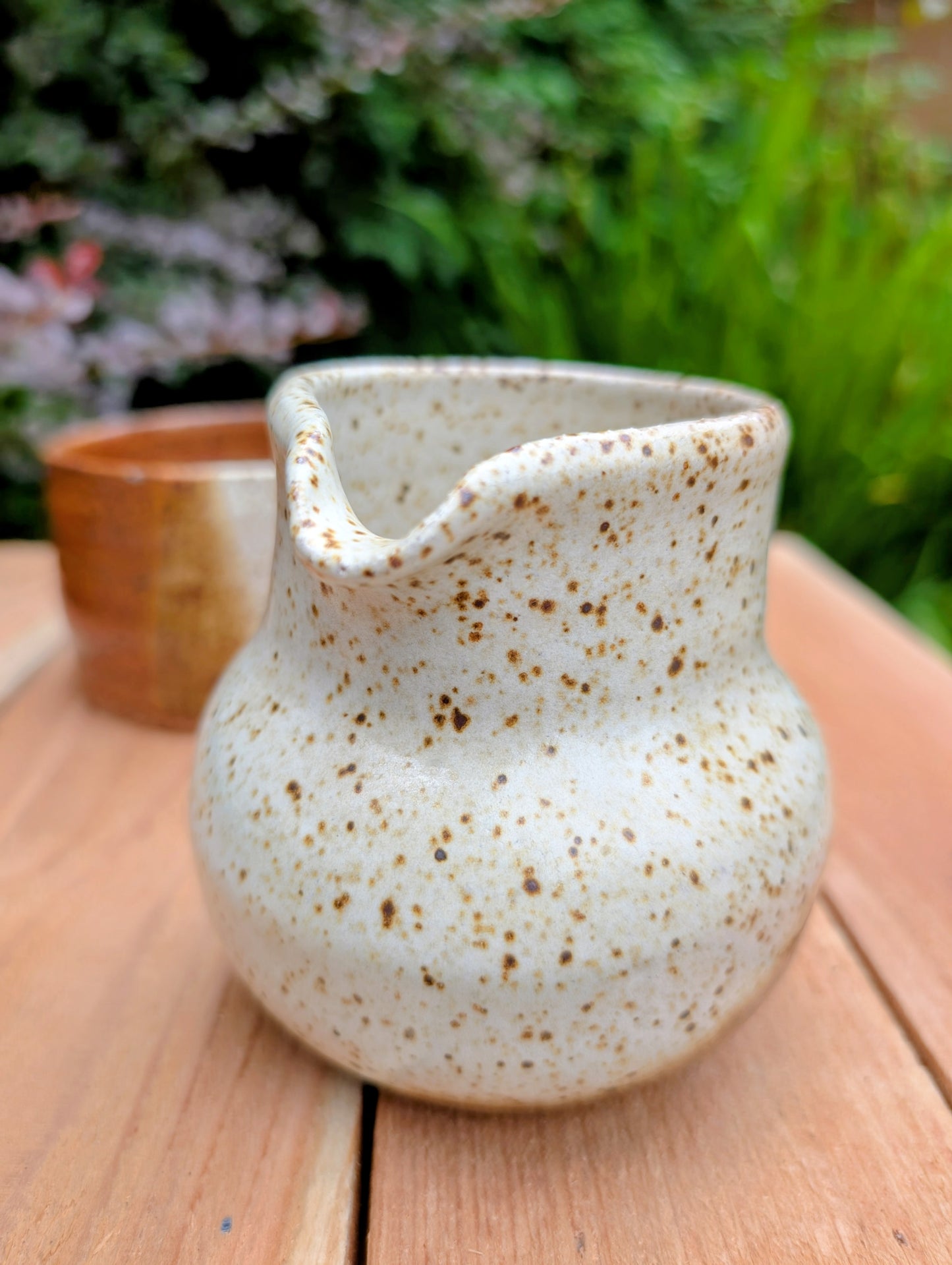 Bring handcrafted warmth to your table with this signed studio pottery creamer and sugar bowl set. Finished in a beautiful speckled cream glaze with flowing olive-brown accents, this artisan stoneware pair blends rustic craftsmanship with timeless everyday function.