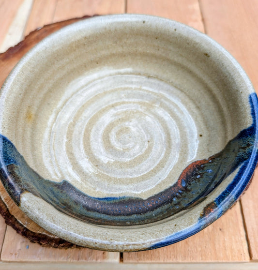 Bring handcrafted warmth to your table with this beautifully wheel-thrown studio pottery bowl, attributed to Gladstone Wear. Featuring flowing cobalt blue, charcoal, and earthy brown glazes over a natural buff stoneware body, it offers timeless artisan appeal for serving or display.