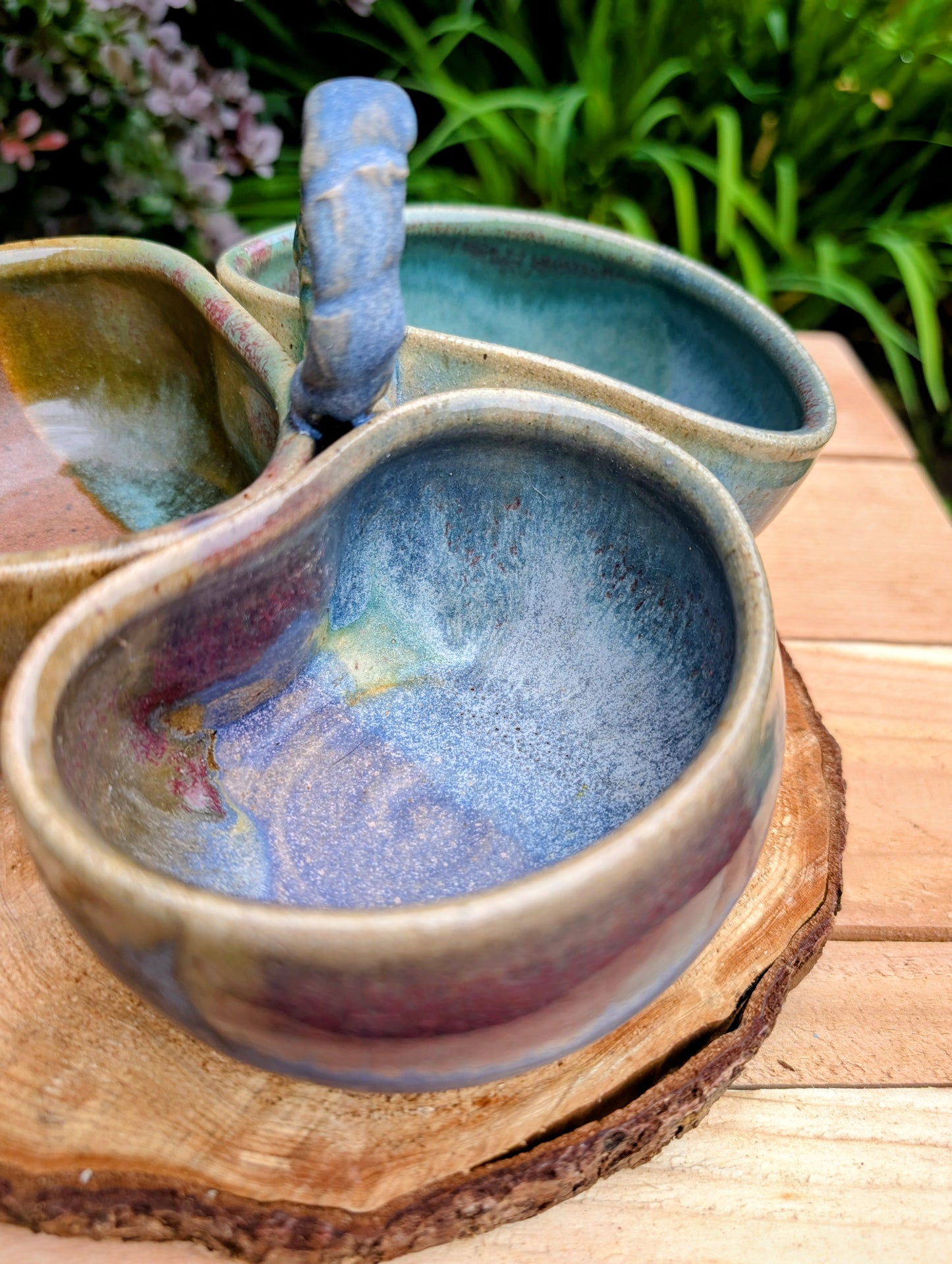 Beautifully handcrafted and artist signed, this three-bowl stoneware condiment server combines sculptural artistry with everyday functionality. Finished in layered seafoam, aqua, moss, and earthy glazes, it brings timeless craftsmanship and Pacific Northwest-inspired beauty to entertaining.