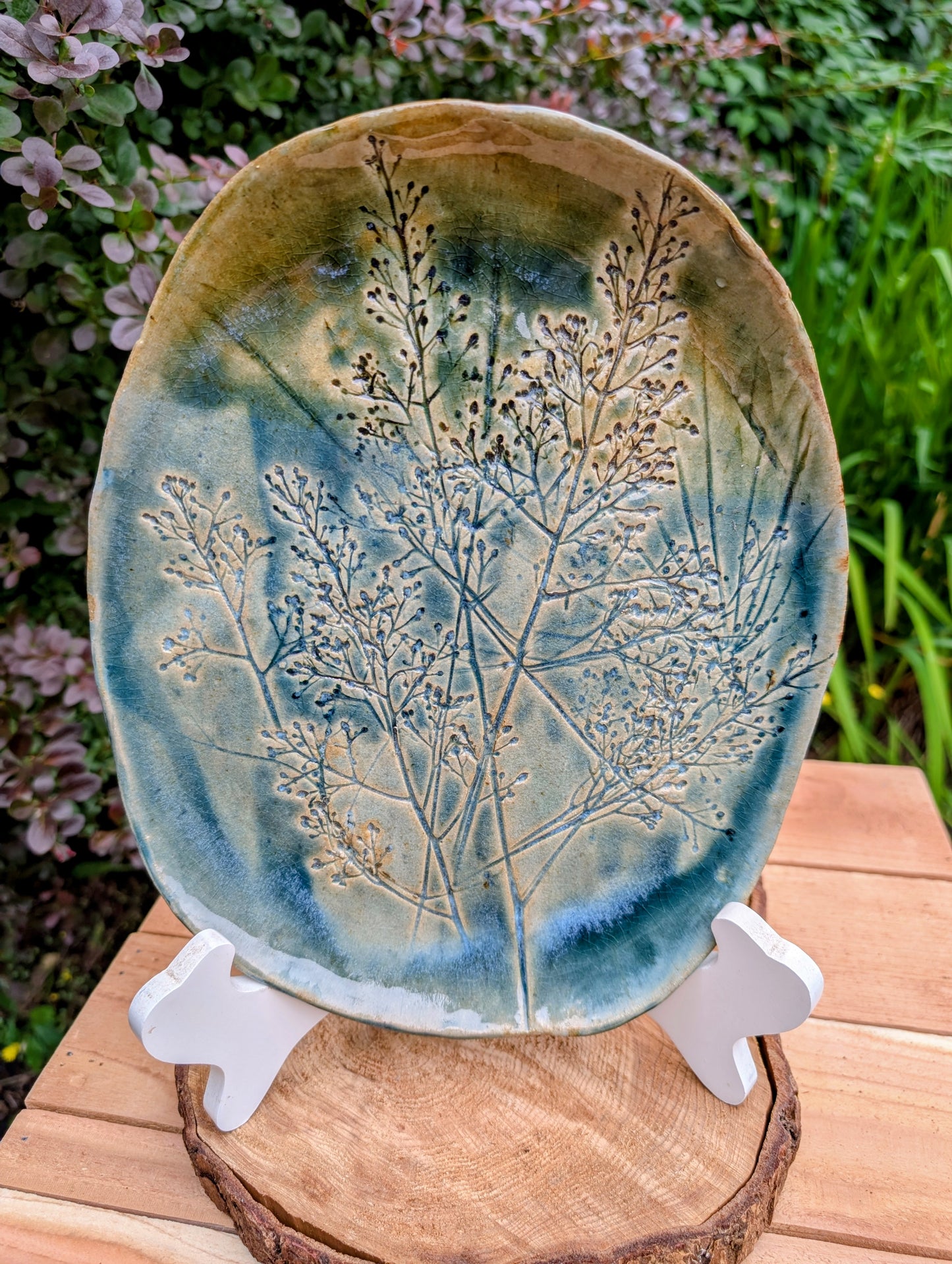 Celebrate the beauty of nature with this signed handbuilt studio pottery platter featuring an elegant botanical relief impressed directly into the clay. Finished in layered blue, teal, and olive glazes, this contemporary stoneware piece is equally at home as functional serveware or displayed as ceramic wall art.