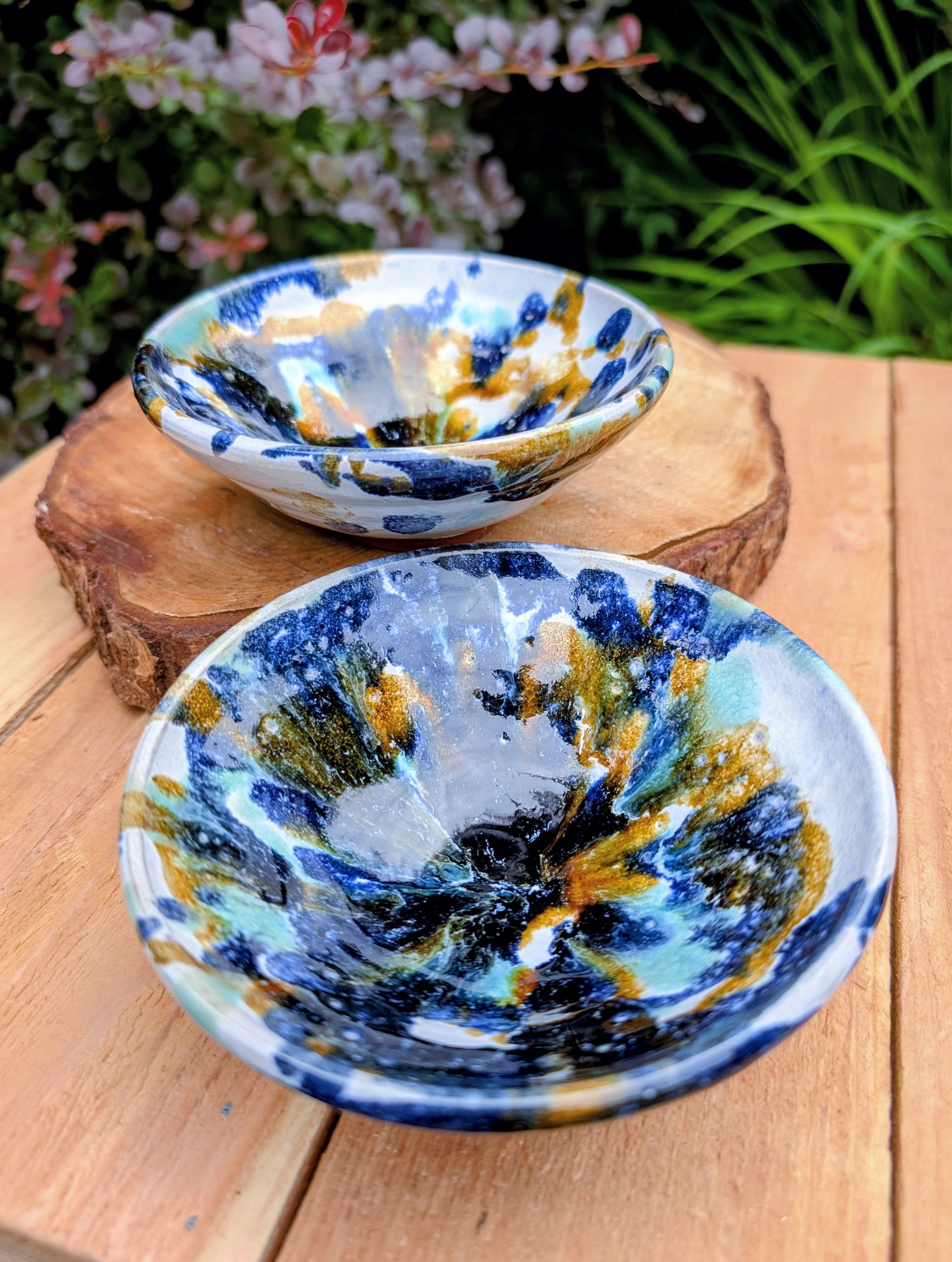 Bring handcrafted artistry to your table with this matching pair of signed studio pottery bowls. Finished with richly layered reactive glazes in cobalt blue, teal, amber, and ivory, these versatile artisan bowls are equally beautiful for entertaining or everyday display.