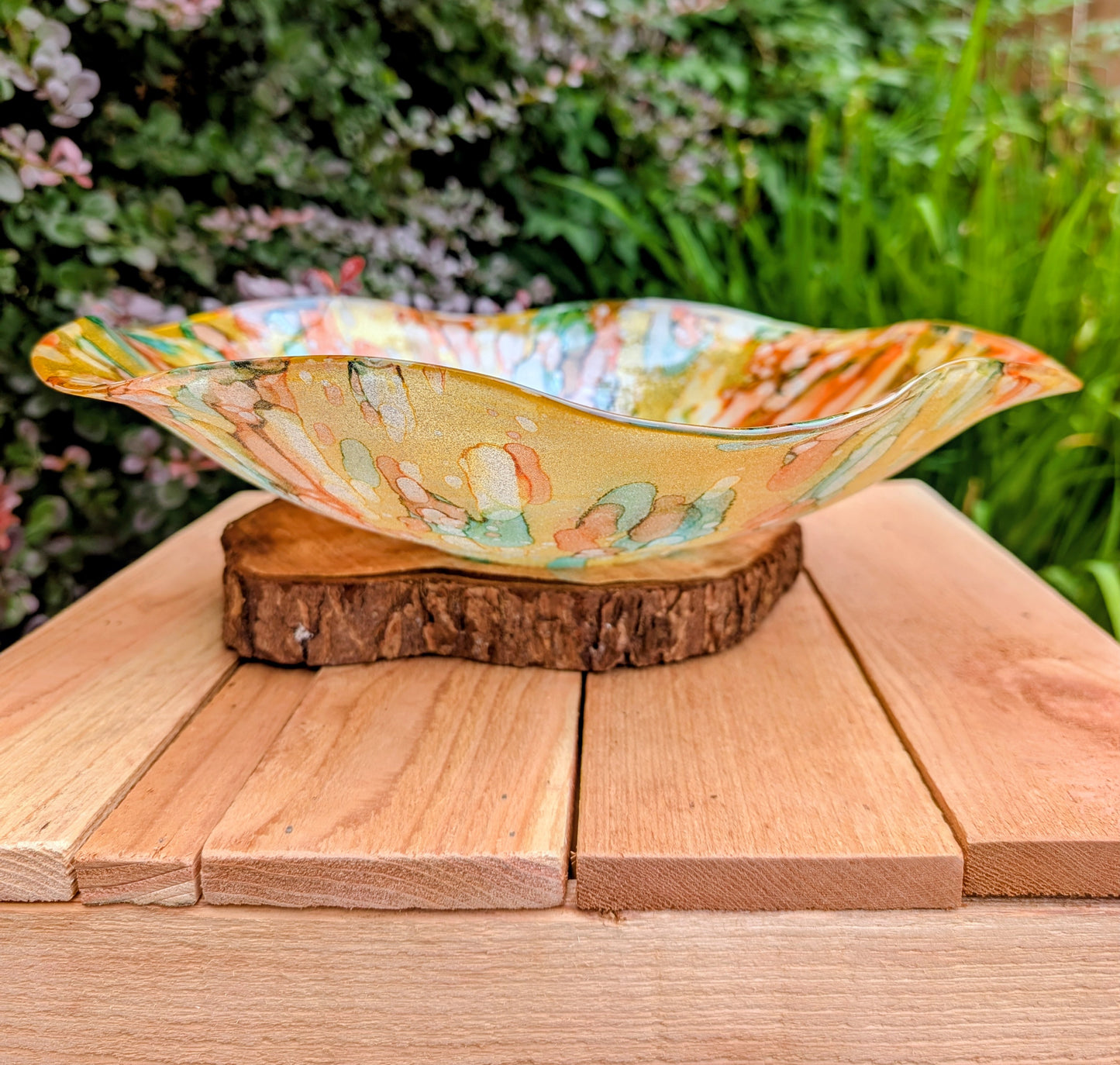 Bring color and light to your home or garden with this contemporary scalloped art glass bowl. Featuring warm golden tones accented by olive green, amber, turquoise, and shimmering metallic highlights, it serves beautifully as a centerpiece, decorative bowl, or tabletop bird bath.