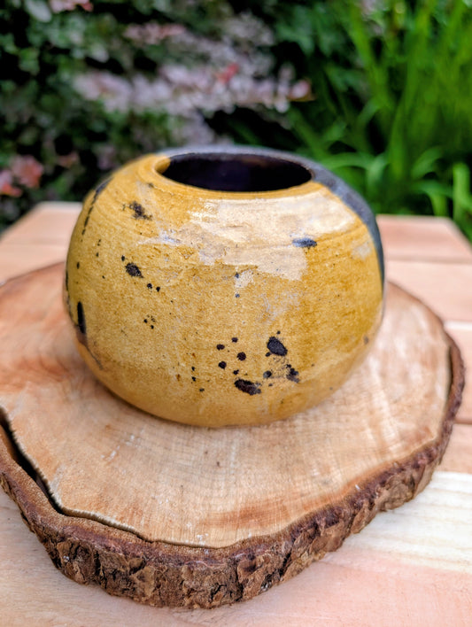 A beautifully hand-thrown studio pottery bud vase dated 1988, featuring a striking half-black, half-mustard glaze accented with expressive iron oxide speckling. Its sculptural form and organic craftsmanship make it equally at home as a minimalist floral vessel or standalone work of ceramic art.