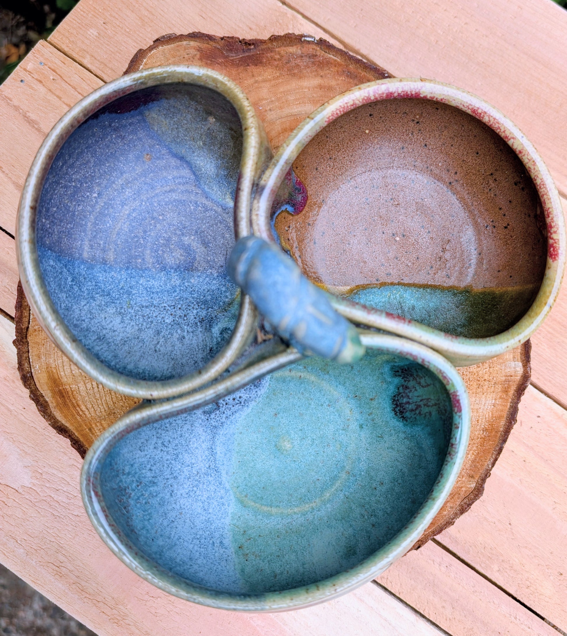Beautifully handcrafted and artist signed, this three-bowl stoneware condiment server combines sculptural artistry with everyday functionality. Finished in layered seafoam, aqua, moss, and earthy glazes, it brings timeless craftsmanship and Pacific Northwest-inspired beauty to entertaining.