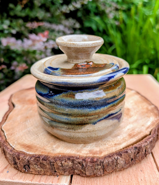 Bring handcrafted warmth to your kitchen with this signed studio pottery lidded jam pot featuring richly layered cobalt blue, olive, brown, and tan glazes. Perfect for serving honey, preserves, sugar, or favorite condiments, this artisan stoneware piece is both beautiful and functional.