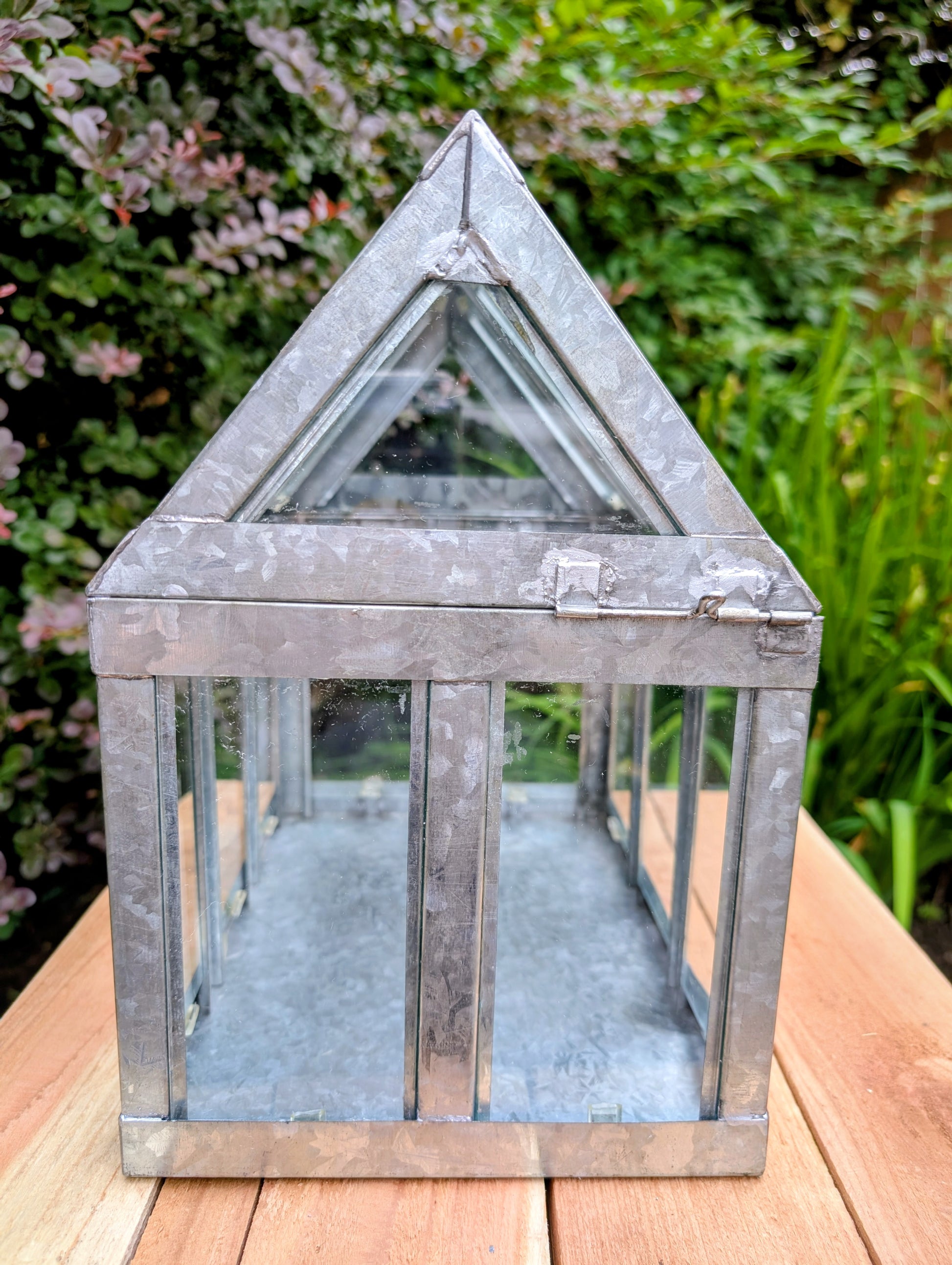 Bring the charm of a Victorian conservatory indoors with this decorative galvanized metal and glass tabletop greenhouse. Perfect for displaying succulents, moss gardens, candles, seasonal décor, or treasured collectibles, it adds timeless botanical style to any room.