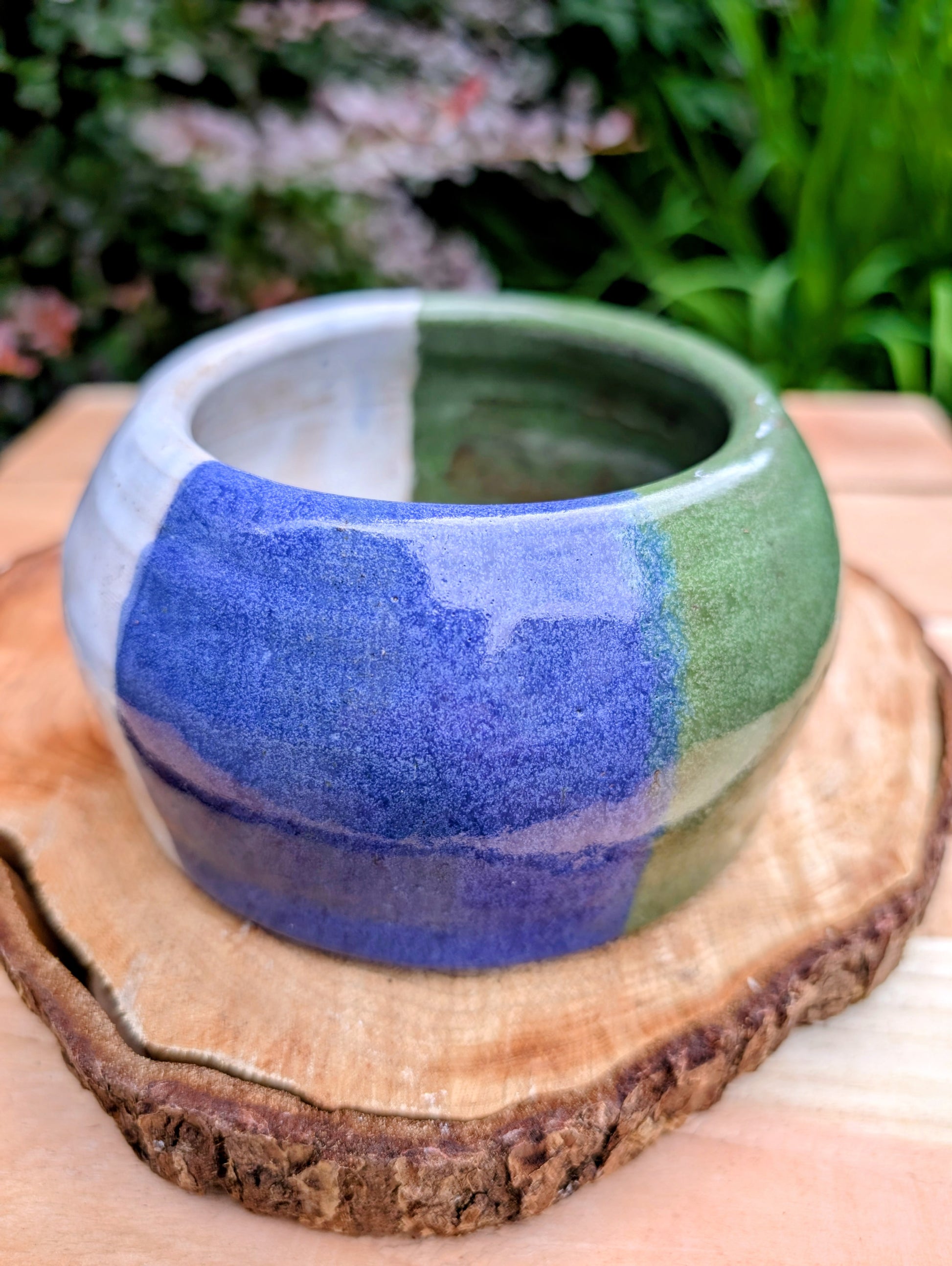 A beautifully hand-thrown studio pottery succulent planter featuring layered blue, moss green, and soft white glazes over high-fired stoneware. Complete with an integrated drainage hole and signed by the artist with the monogram "G.M.," this artisan planter brings handcrafted character to any home or garden.