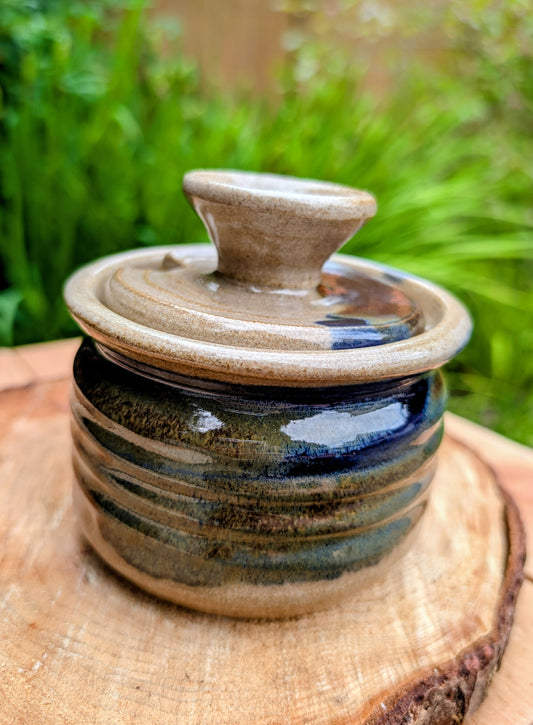Bring handcrafted warmth to your kitchen with this signed studio pottery lidded jam pot featuring richly layered cobalt blue, olive, brown, and tan glazes. Perfect for serving honey, preserves, sugar, or favorite condiments, this artisan stoneware piece is both beautiful and functional.