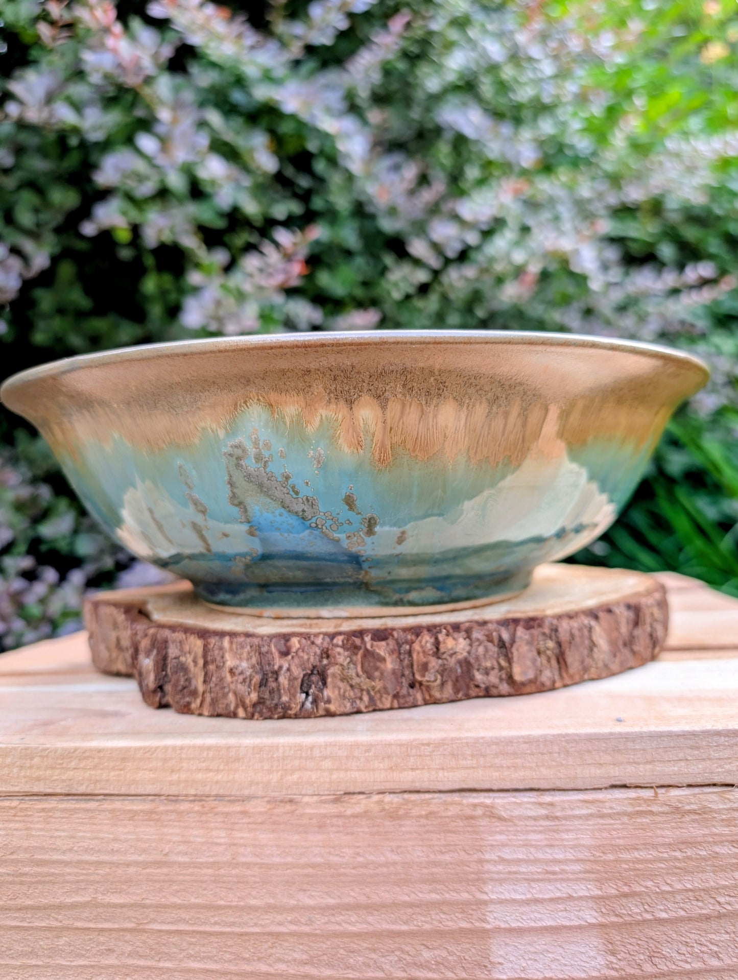 A beautifully handcrafted studio pottery bowl featuring layered blue, celadon, and copper reactive glazes with striking crystalline patterning. This artisan stoneware piece makes an eye-catching centerpiece or decorative accent inspired by the colors of Pacific Northwest waters.