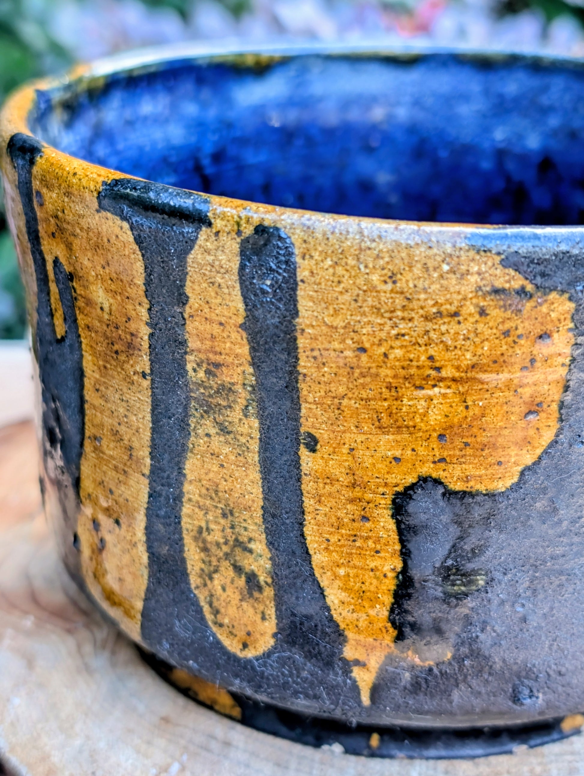 A beautifully hand-thrown studio pottery bowl featuring a rich cobalt blue interior, earthy ochre exterior, and expressive black drip glaze. Its timeless craftsmanship and organic design make it equally suited for serving, display, or adding artisan character to any Pacific Northwest-inspired home.