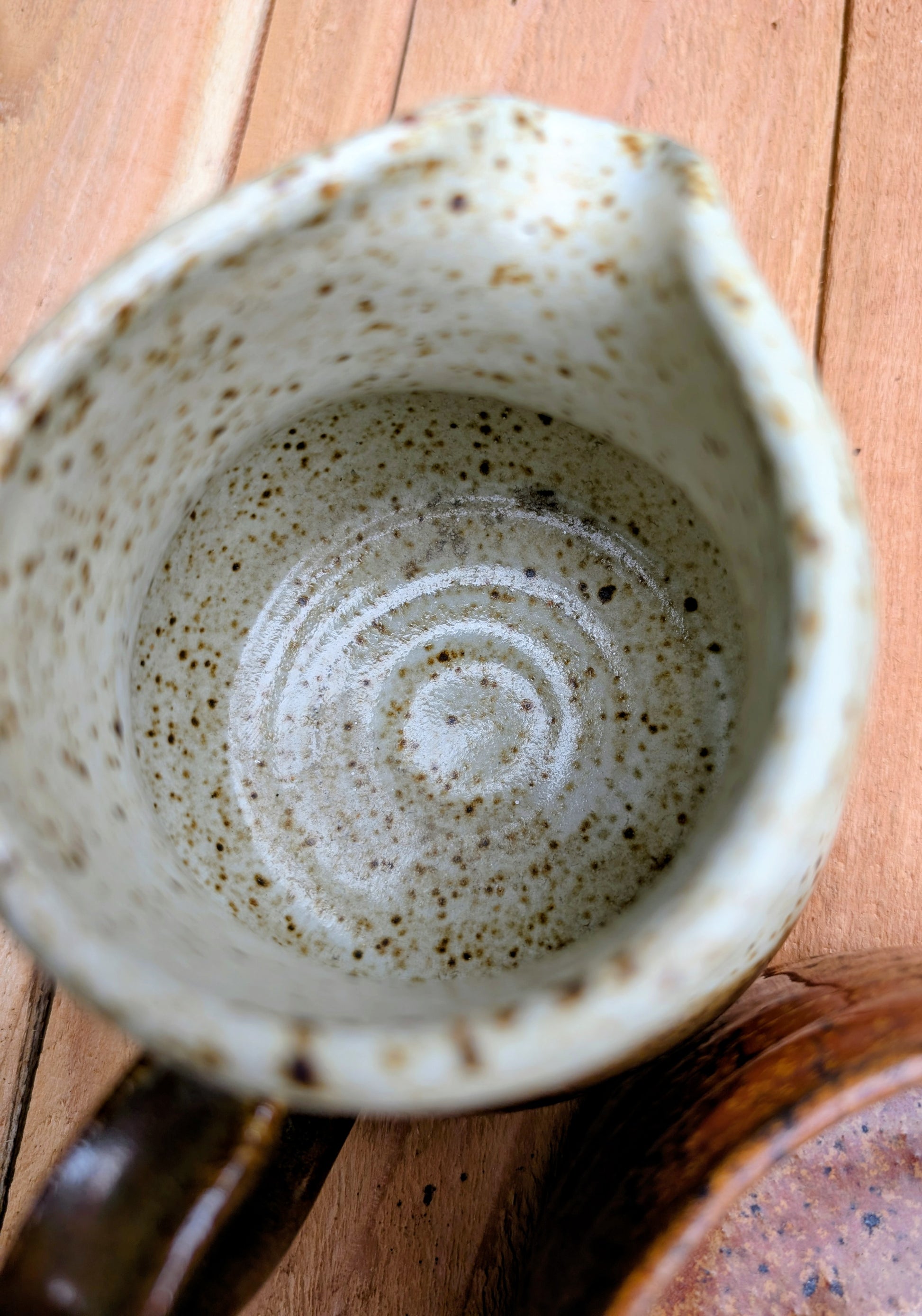 Bring handcrafted warmth to your table with this signed studio pottery creamer and sugar bowl set. Finished in a beautiful speckled cream glaze with flowing olive-brown accents, this artisan stoneware pair blends rustic craftsmanship with timeless everyday function.