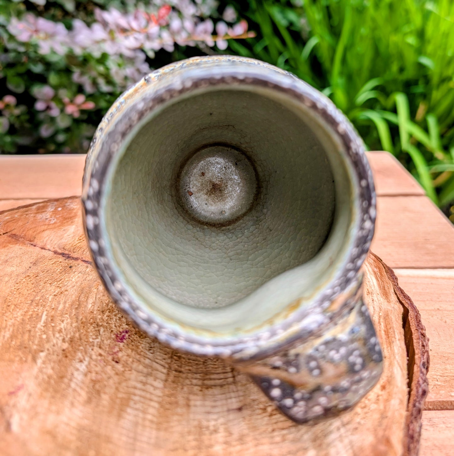 Celebrate slow mornings with this handcrafted faceted studio pottery mug, featuring a richly layered volcanic glaze and a soft celadon-green interior. Its sculptural form and earthy palette make it equally beautiful in the hand or displayed as functional art.