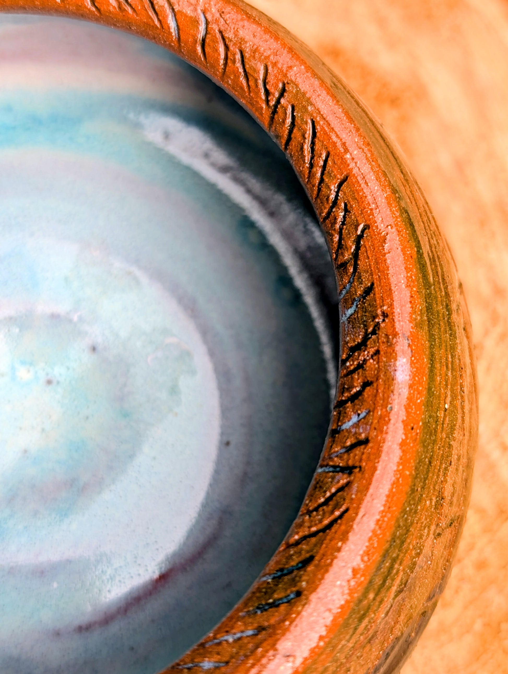Handcrafted with richly carved texture and a soft blue reactive glaze, this signed studio pottery bowl brings warmth and character to any home. Ideal as a serving bowl, decorative accent, or functional piece of everyday artisan pottery.
