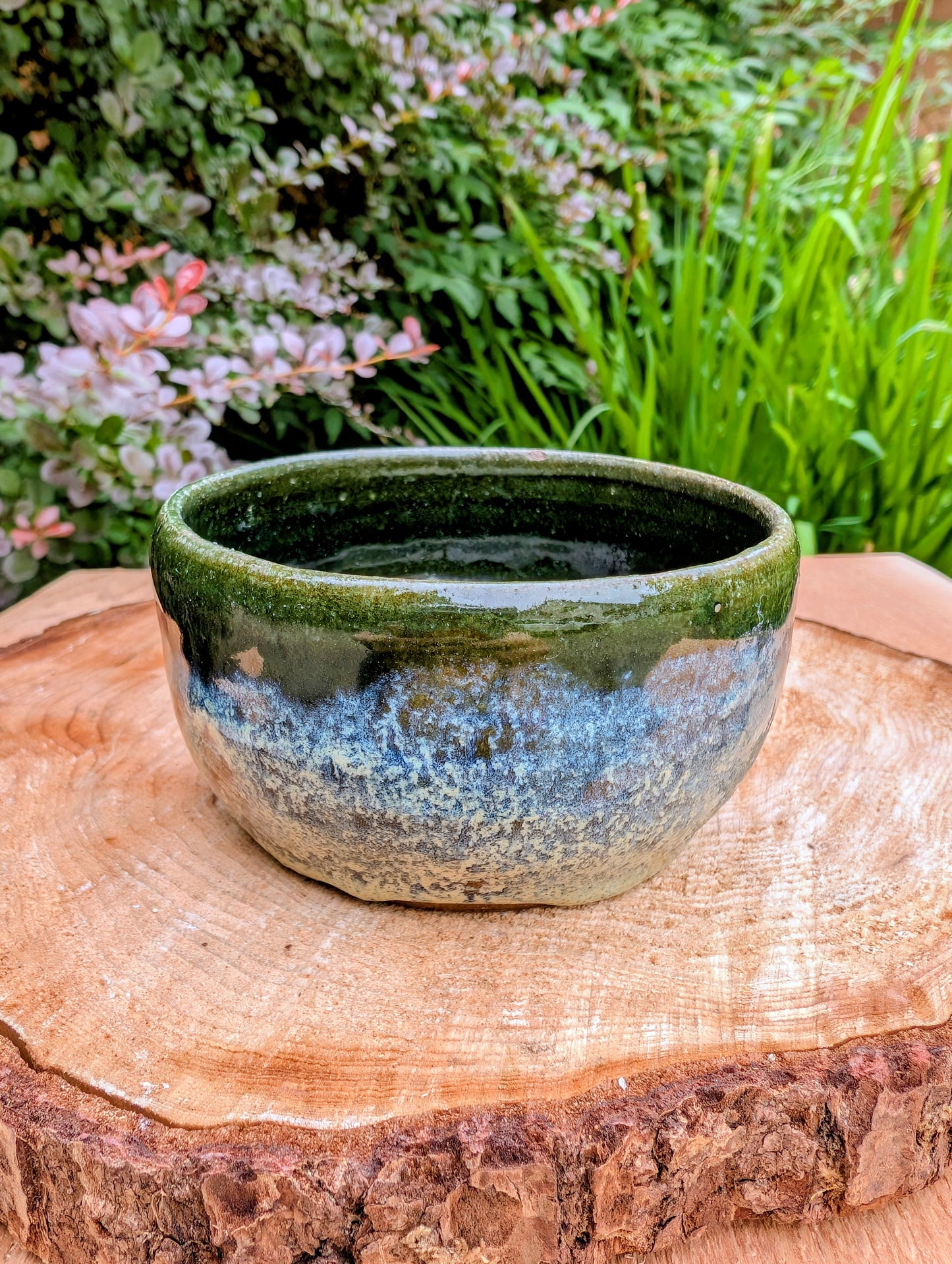 A beautifully hand-thrown studio pottery bowl featuring a rich olive green interior and layered blue, cream, and earthy brown glaze. Signed by the artist, this compact stoneware piece blends functional craftsmanship with timeless Pacific Northwest style.