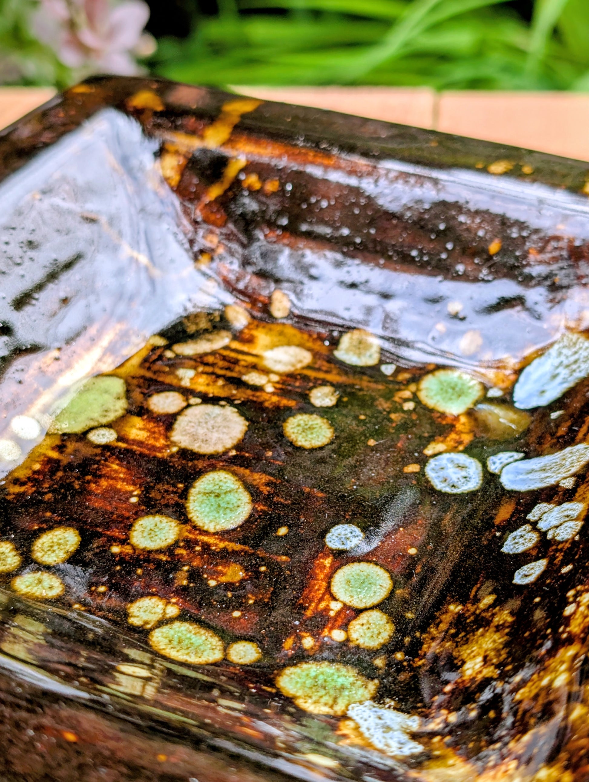 Bring handcrafted artistry into your home with this one-of-a-kind square studio pottery dish. Its rich chocolate brown glaze is accented by constellation-like blue, green, and cream crystalline details, making it equally beautiful as a decorative catchall, appetizer dish, or display piece.