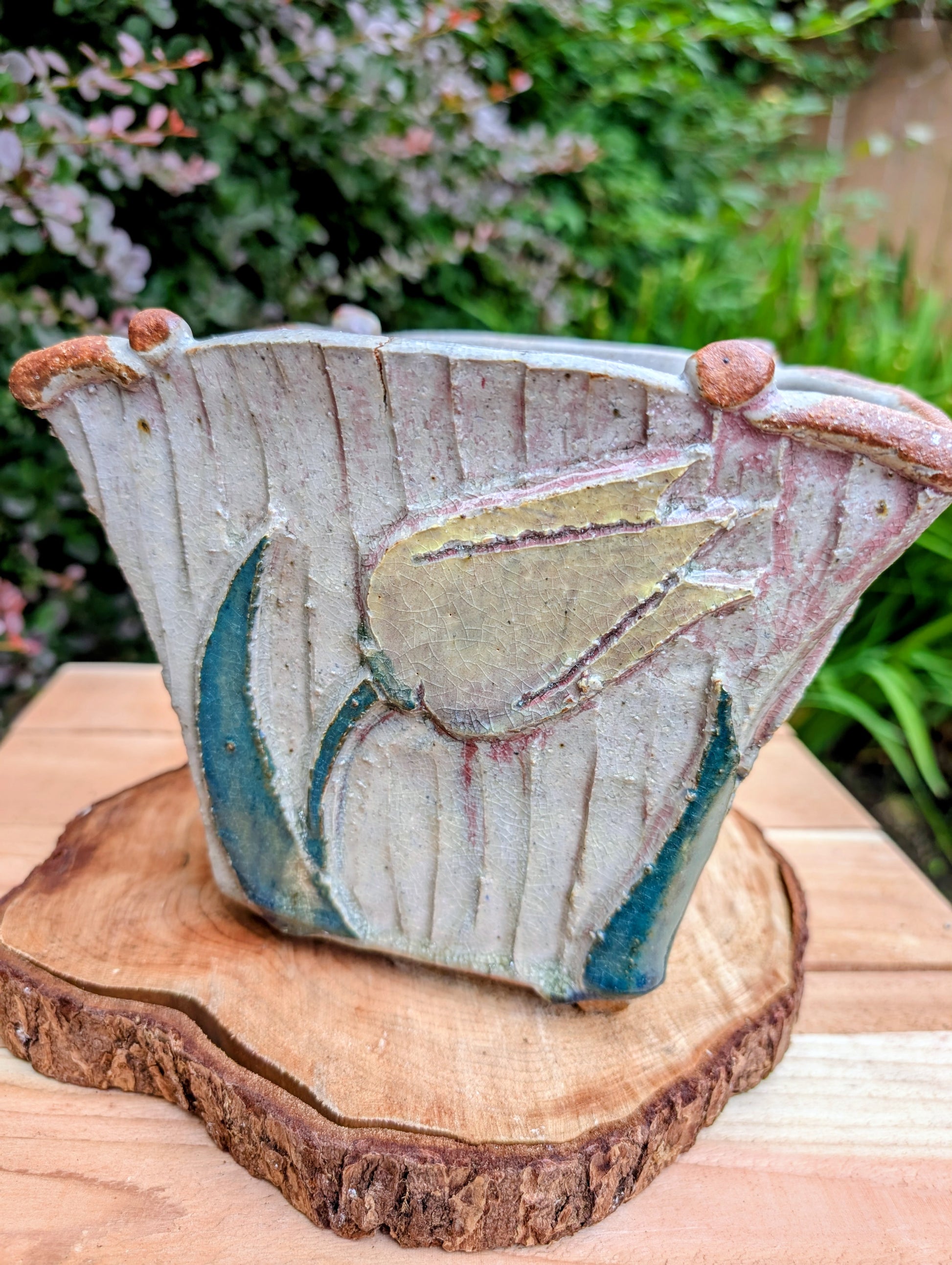 Celebrate handcrafted artistry with this handbuilt stoneware vase or cachepot featuring sculpted tulip relief panels, rich matte glazes, and an architectural four-footed form. Its organic botanical design makes it equally beautiful as a floral vessel, planter, or sculptural accent.