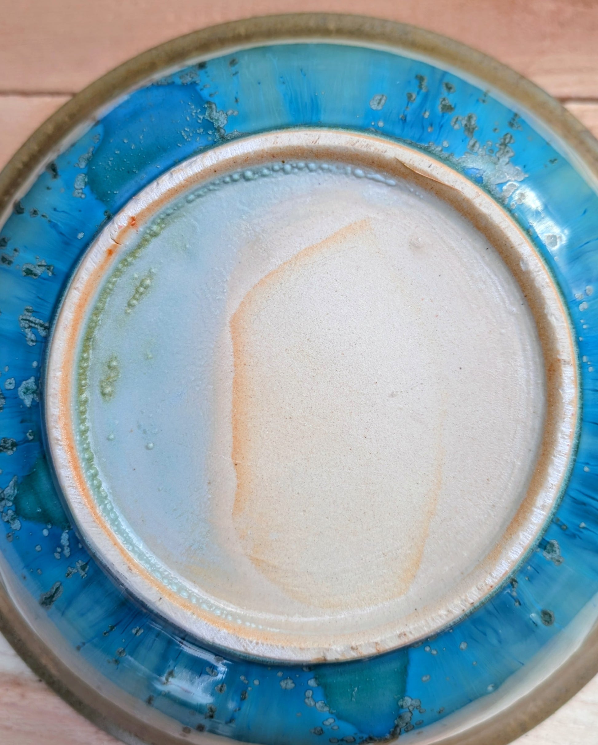 A beautifully handcrafted studio pottery bowl featuring layered blue, celadon, and copper reactive glazes with striking crystalline patterning. This artisan stoneware piece makes an eye-catching centerpiece or decorative accent inspired by the colors of Pacific Northwest waters.