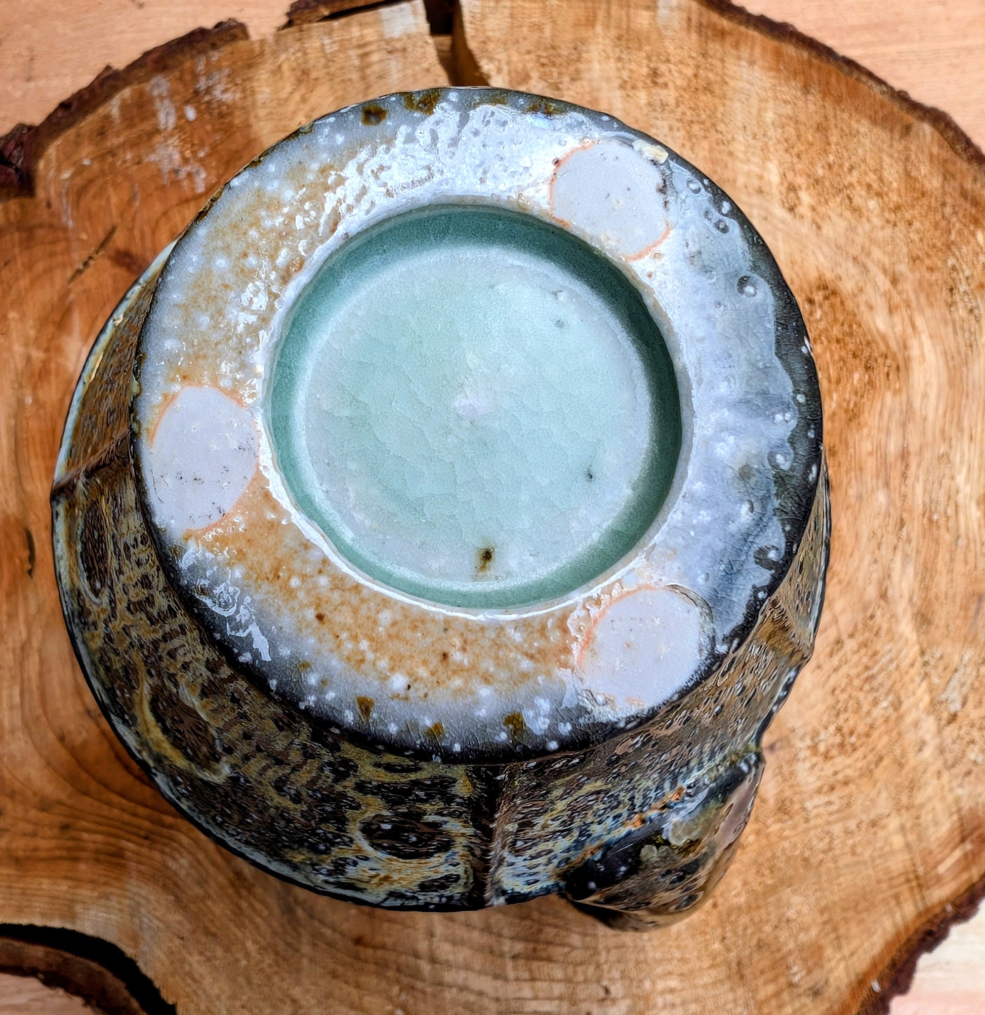 Celebrate slow mornings with this handcrafted faceted studio pottery mug, featuring a richly layered volcanic glaze and a soft celadon-green interior. Its sculptural form and earthy palette make it equally beautiful in the hand or displayed as functional art.