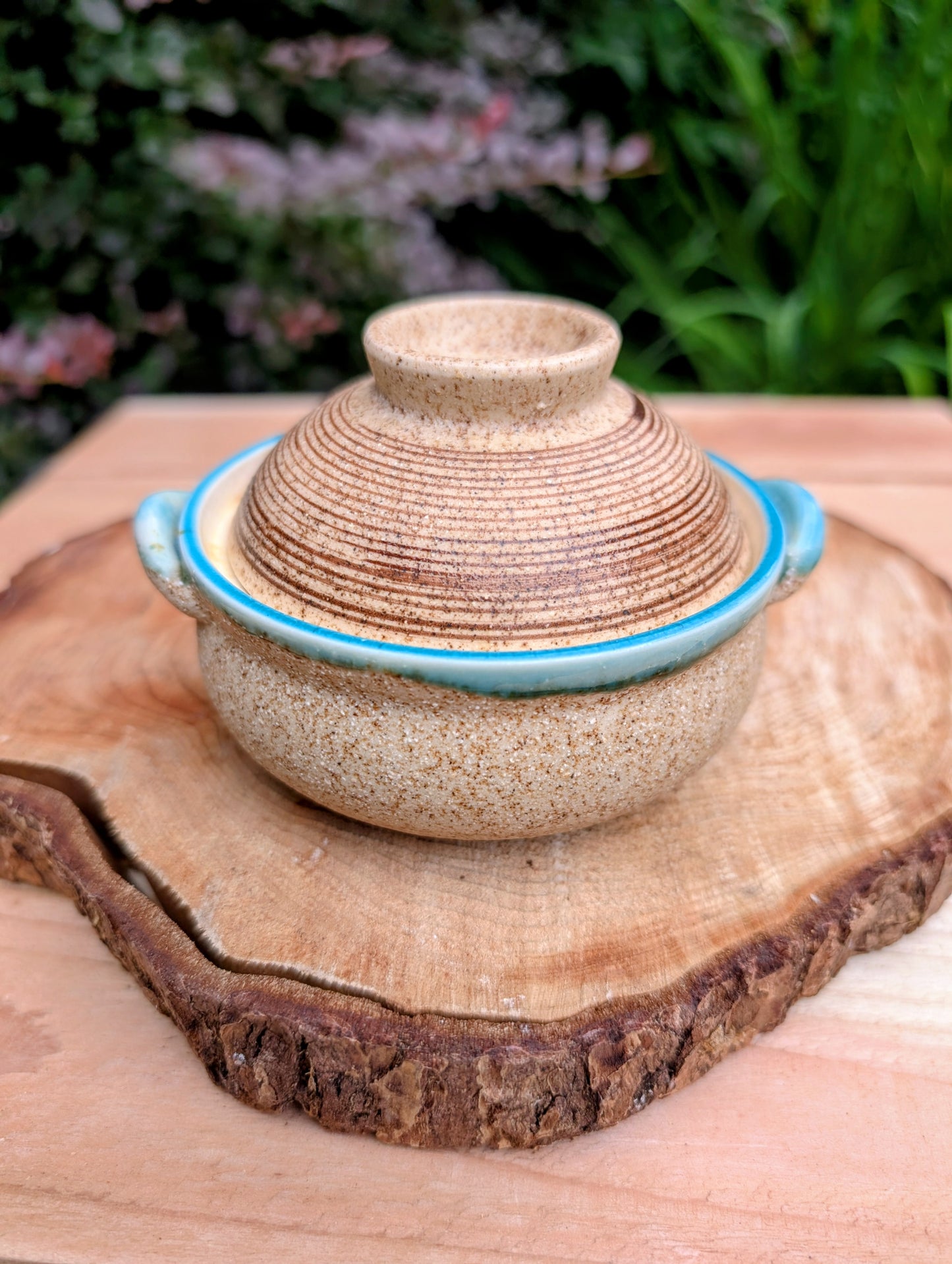 A beautifully handcrafted studio pottery bowl featuring a warm speckled stoneware exterior, vibrant turquoise glazed interior, and matching ribbed lid. Its compact size and organic design make it perfect for serving small dishes or displaying as a timeless piece of artisan pottery.