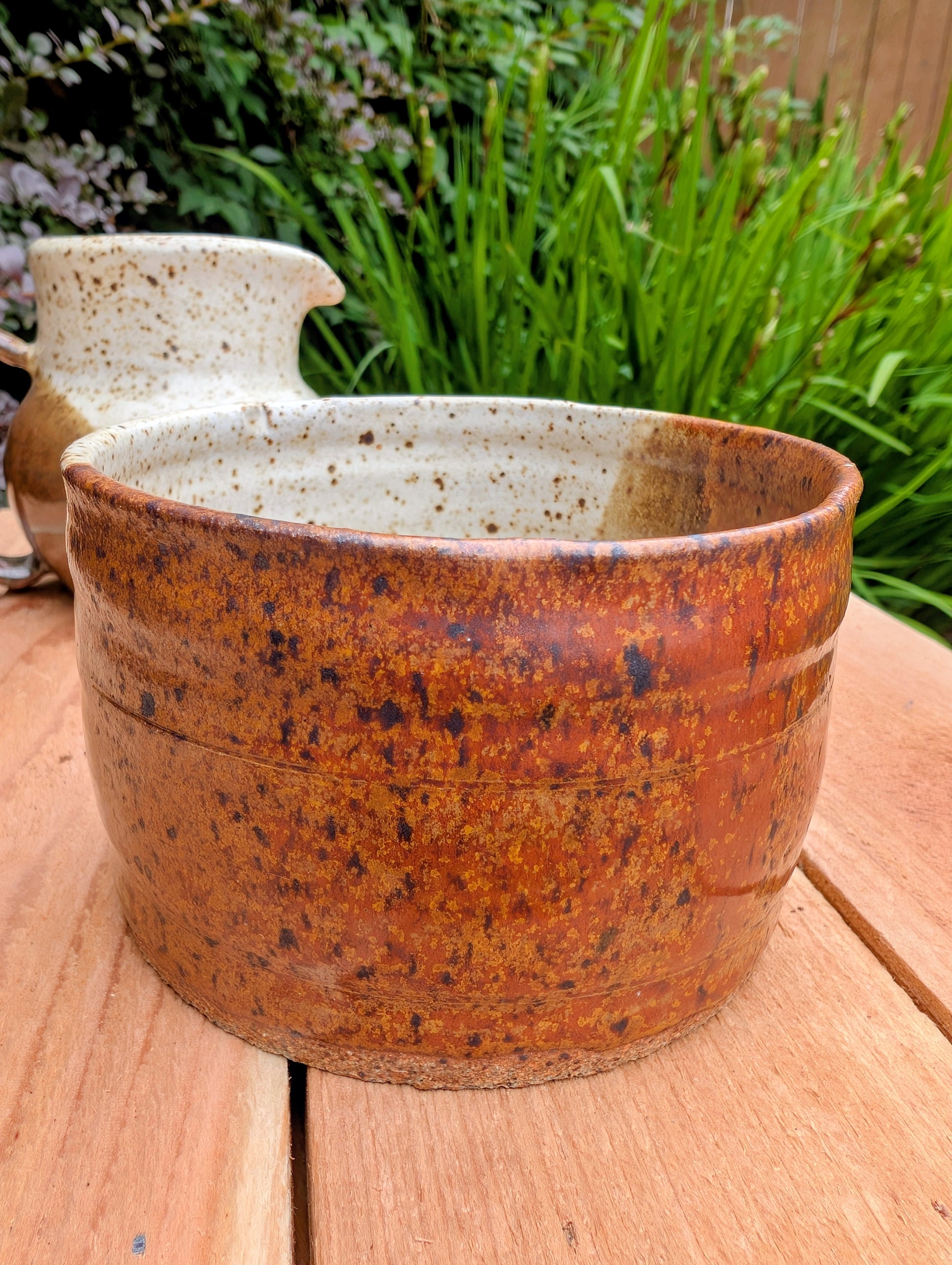 Bring handcrafted warmth to your table with this signed studio pottery creamer and sugar bowl set. Finished in a beautiful speckled cream glaze with flowing olive-brown accents, this artisan stoneware pair blends rustic craftsmanship with timeless everyday function.