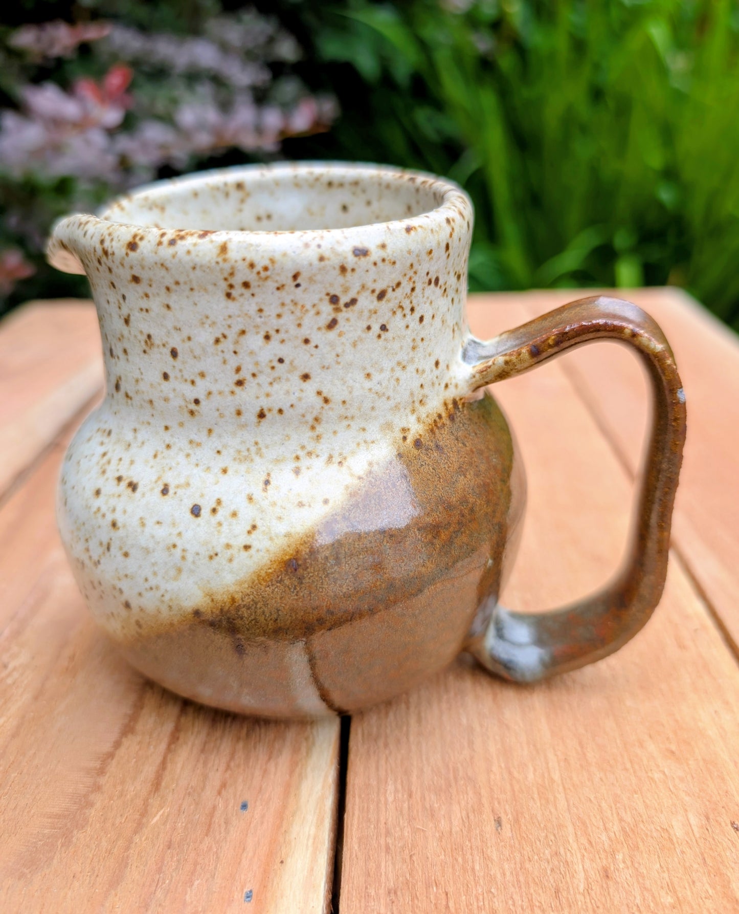 Bring handcrafted warmth to your table with this signed studio pottery creamer and sugar bowl set. Finished in a beautiful speckled cream glaze with flowing olive-brown accents, this artisan stoneware pair blends rustic craftsmanship with timeless everyday function.