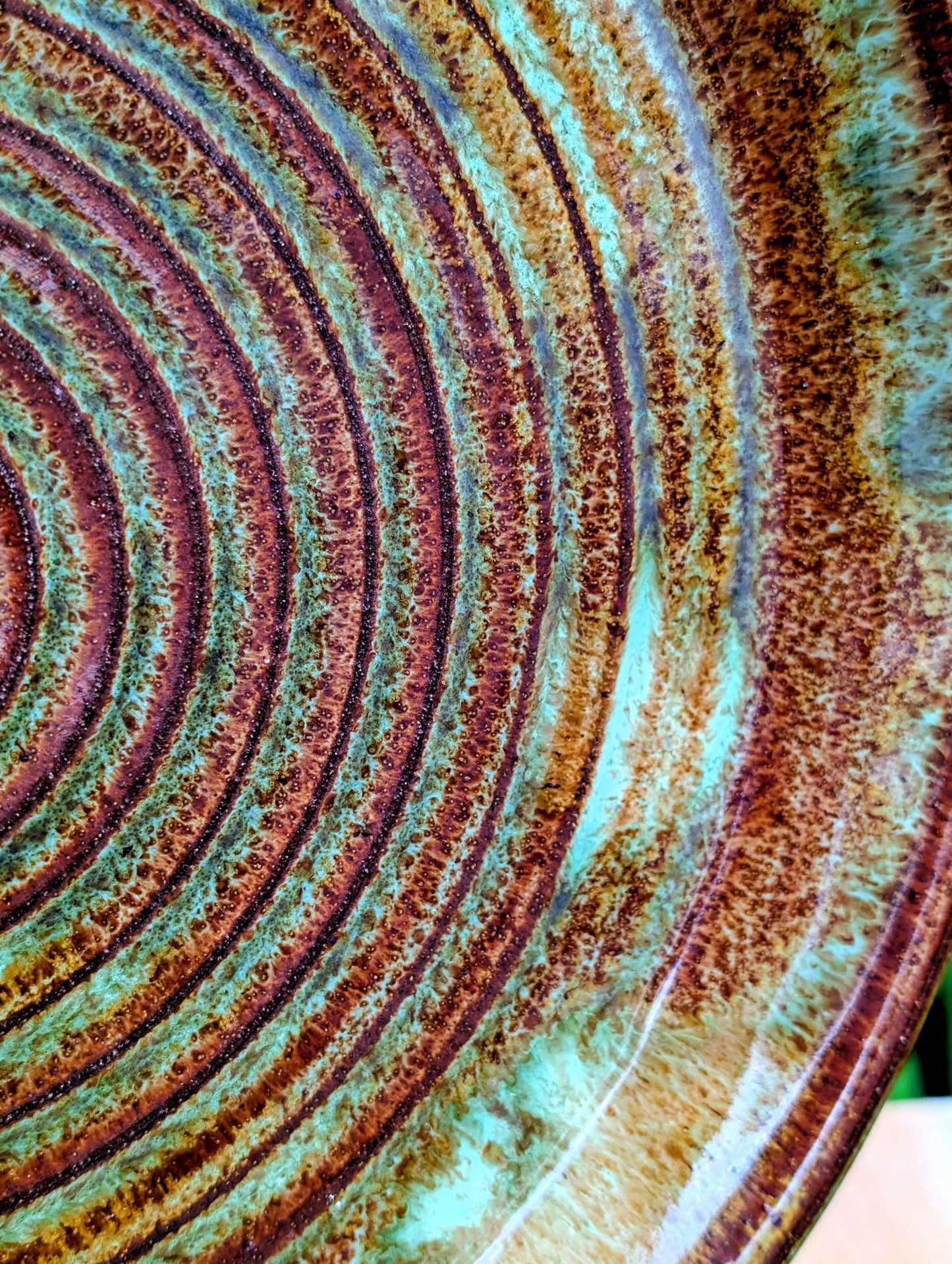 A beautifully hand-thrown studio pottery charger featuring an impressed spiral design and richly variegated moss green and rust glazes. This substantial signed stoneware piece brings timeless craftsmanship and Pacific Northwest-inspired warmth to shelves, tables, or wall displays.