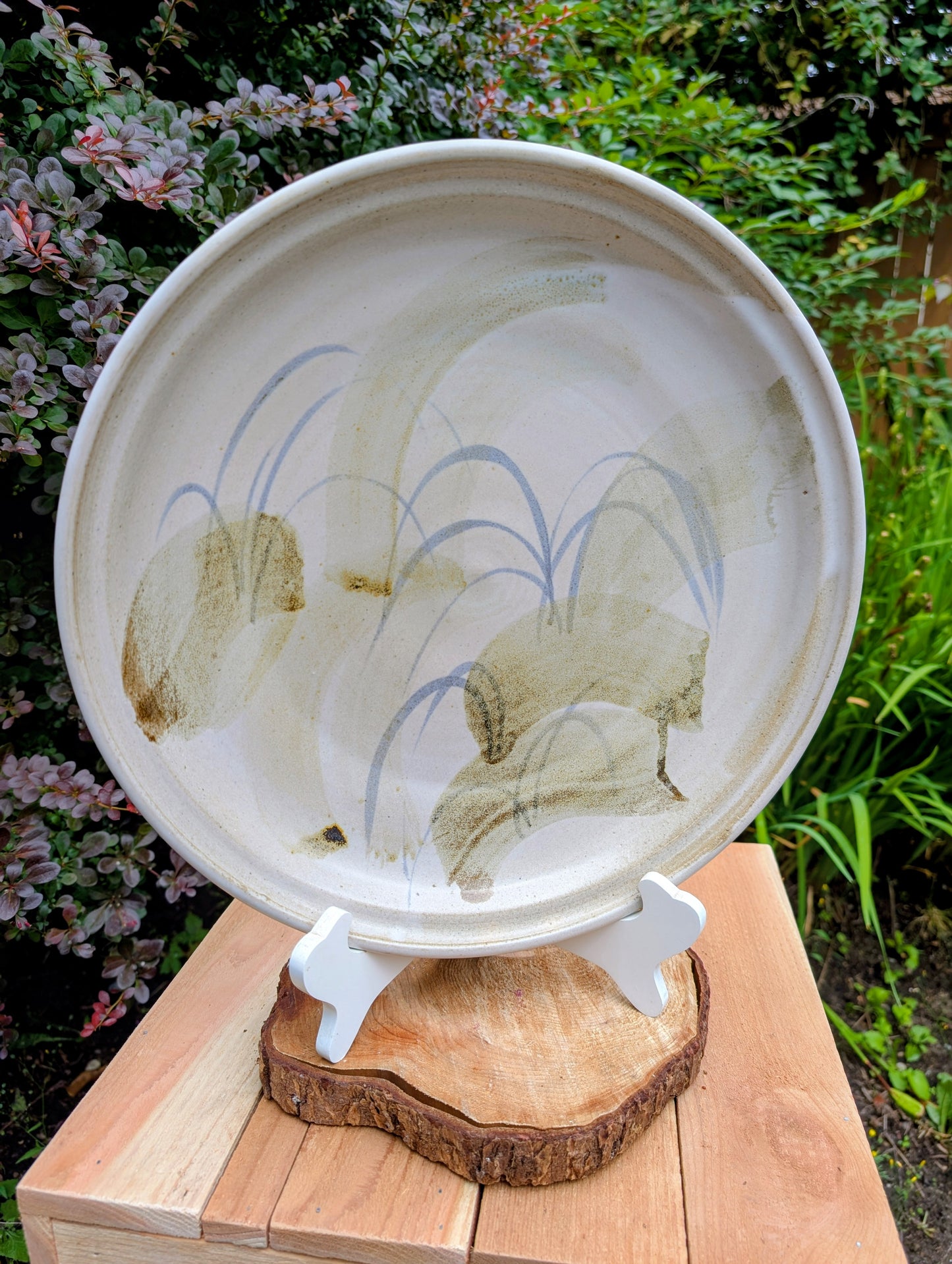 A beautifully hand-thrown studio pottery platter featuring expressive blue-gray and olive brushwork over a soft neutral glaze. Its generous size and timeless craftsmanship make it equally suited for serving, display, or as striking wall décor.