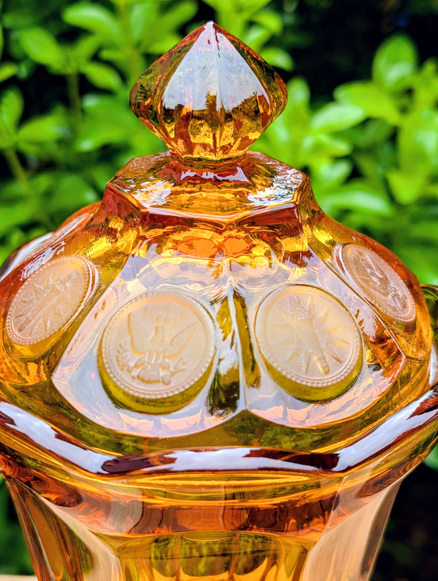 A stunning matching set of vintage Indiana Glass in the iconic Kings Crown (Coin) pattern. This coordinated amber glass collection includes a covered pedestal vase and matching covered candy dish, each with its original lid. A beautiful Mid-Century display for collectors and vintage home décor enthusiasts.