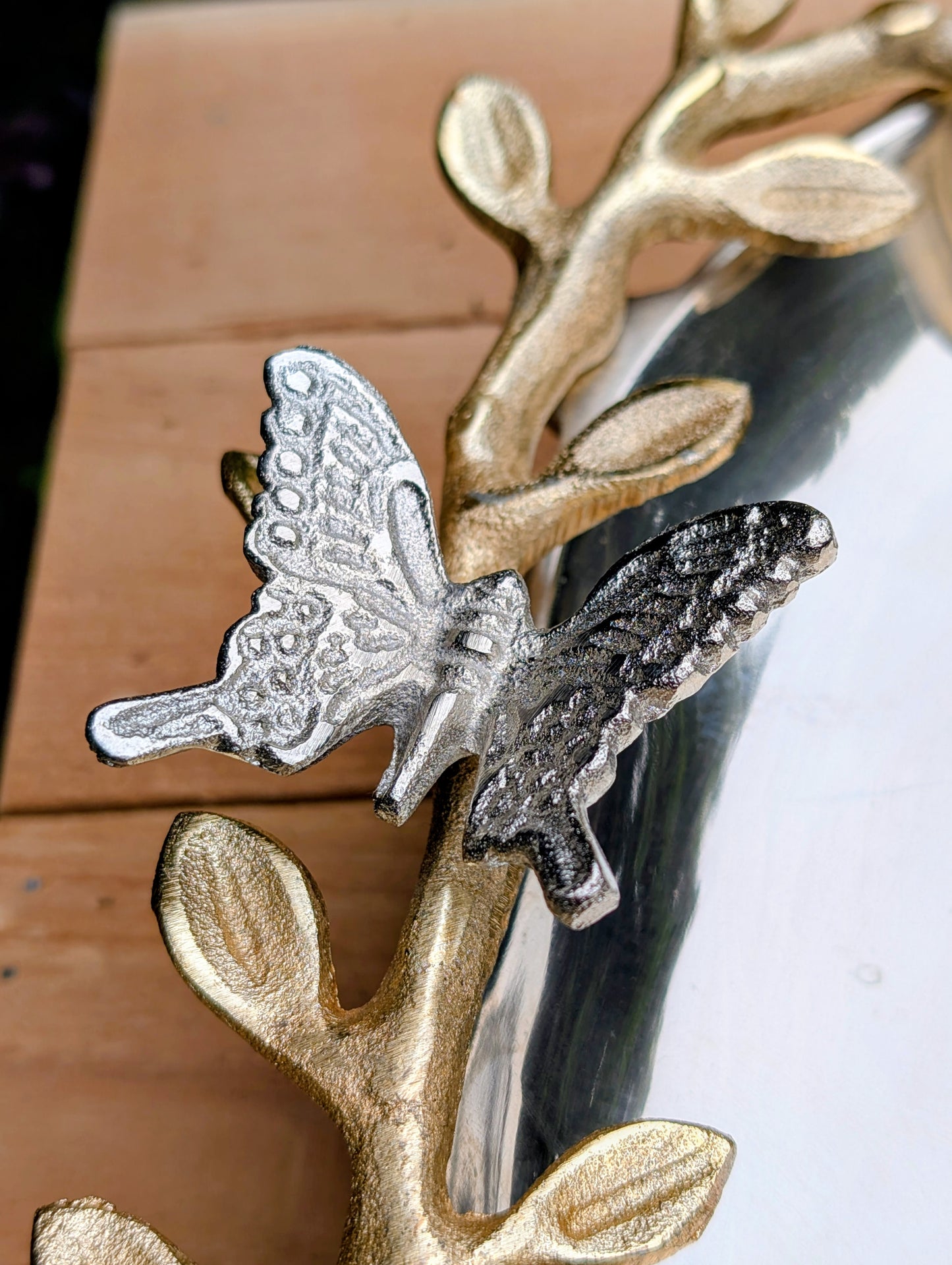 Bring the beauty of the forest indoors with this elegant cast aluminum serving platter featuring sculpted gold-tone branch handles and a delicate butterfly accent. Equally suited for entertaining or displaying seasonal décor, this nature-inspired piece blends organic artistry with timeless metallic finishes.