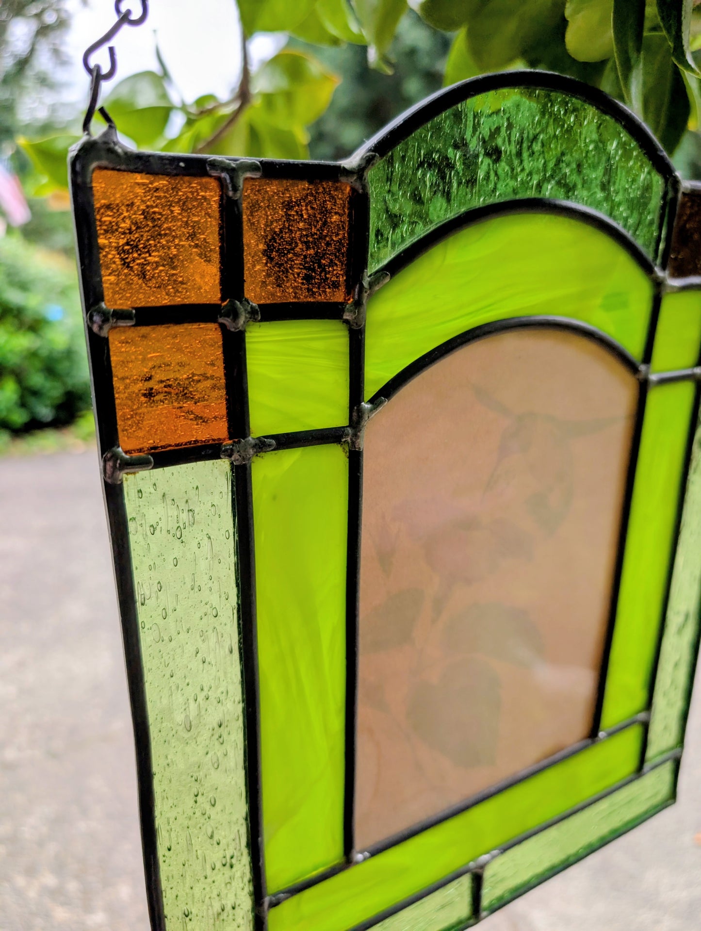 Bring the beauty of a hummingbird in bloom into your home with this handcrafted stained glass hanging panel. Featuring vibrant textured art glass surrounding a detailed hummingbird and hibiscus centerpiece, it catches natural light beautifully and adds year-round color to any window, sunroom, or garden-inspired space.