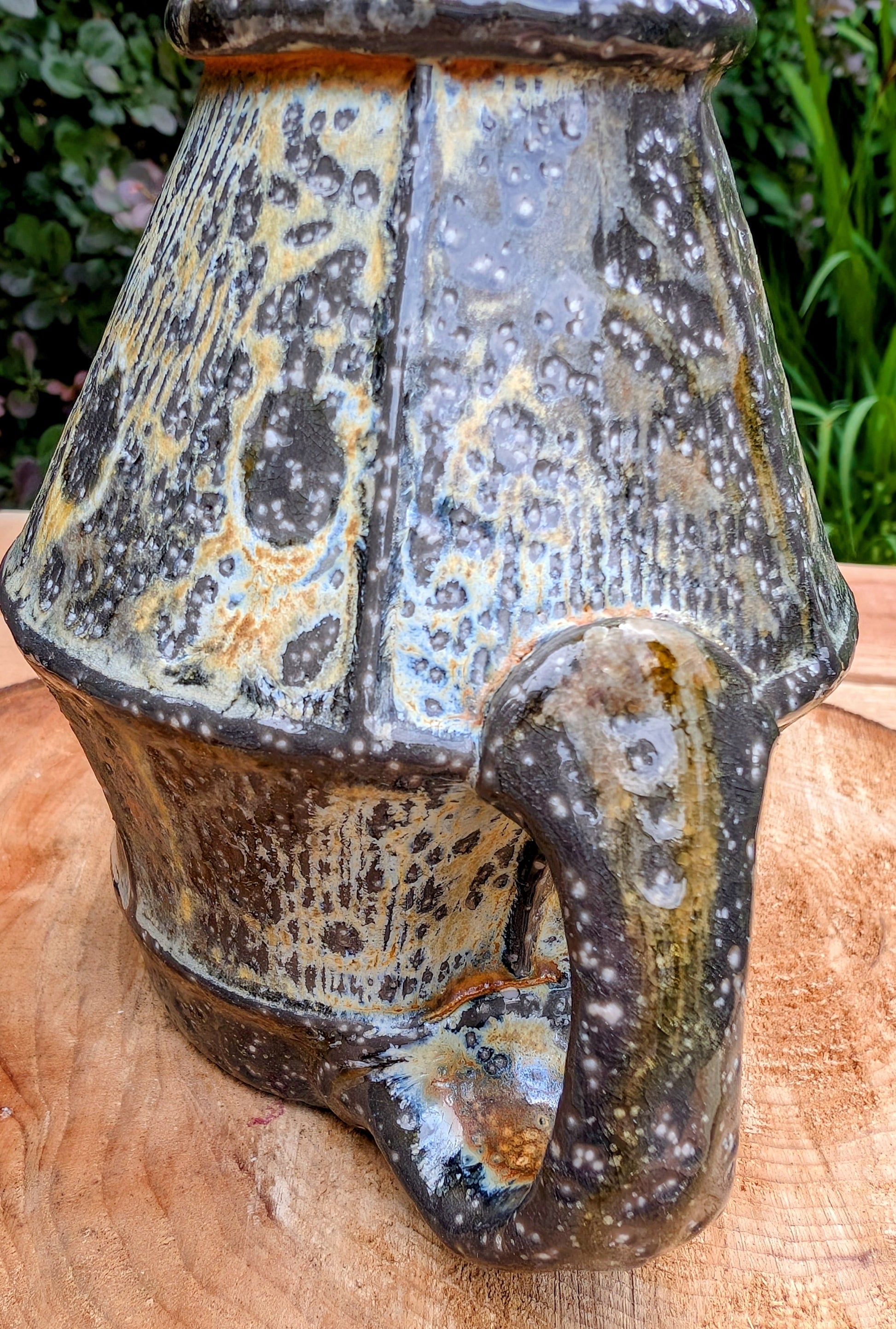 Celebrate slow mornings with this handcrafted faceted studio pottery mug, featuring a richly layered volcanic glaze and a soft celadon-green interior. Its sculptural form and earthy palette make it equally beautiful in the hand or displayed as functional art.