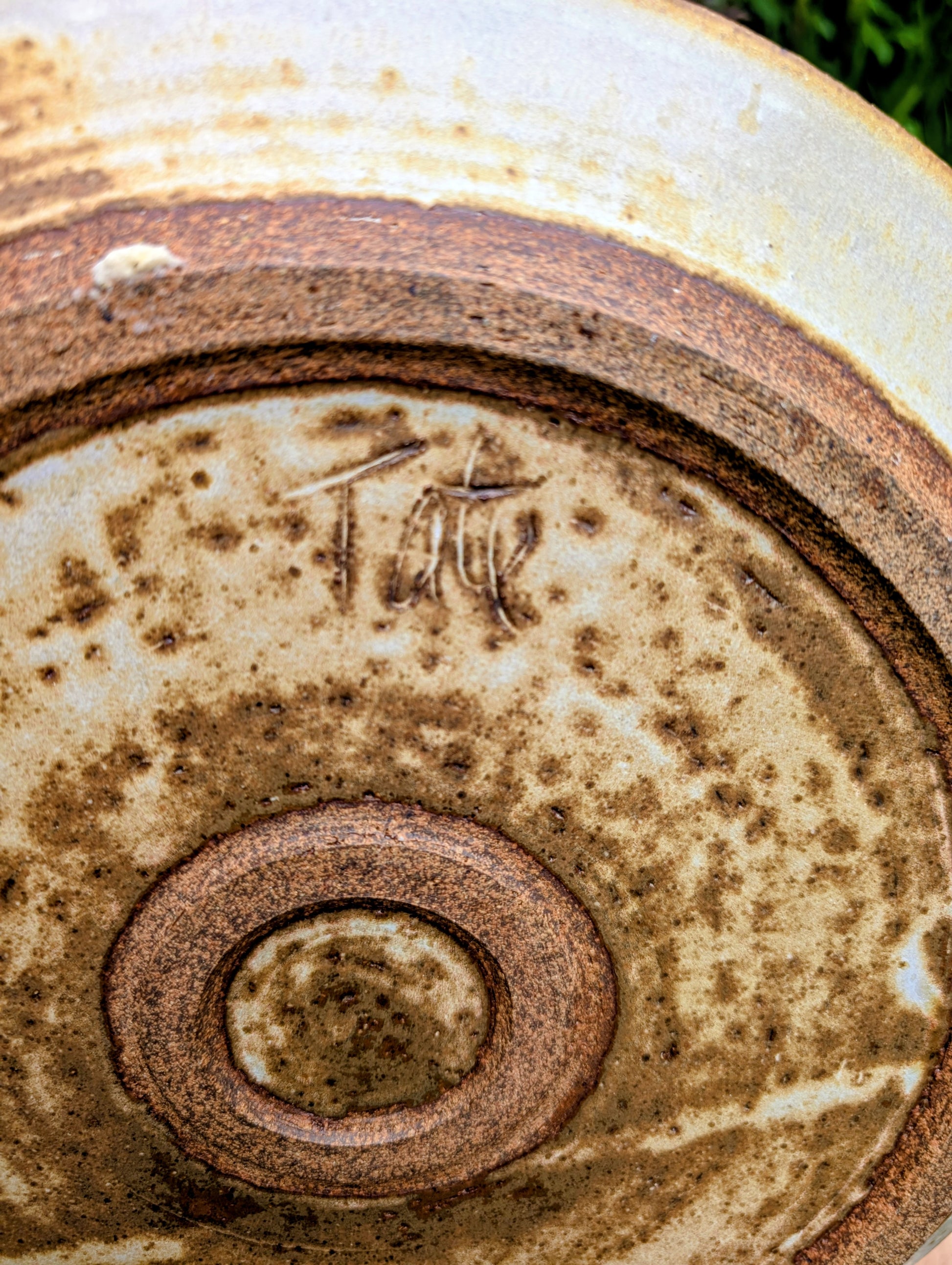 A striking hand-thrown studio pottery platter featuring an expressive cream, maroon, and olive glaze composition with visible throwing rings and an incised artist signature. Beautiful as both a decorative wall display and a functional serving piece, it embodies the warmth and craftsmanship of contemporary American studio ceramics.