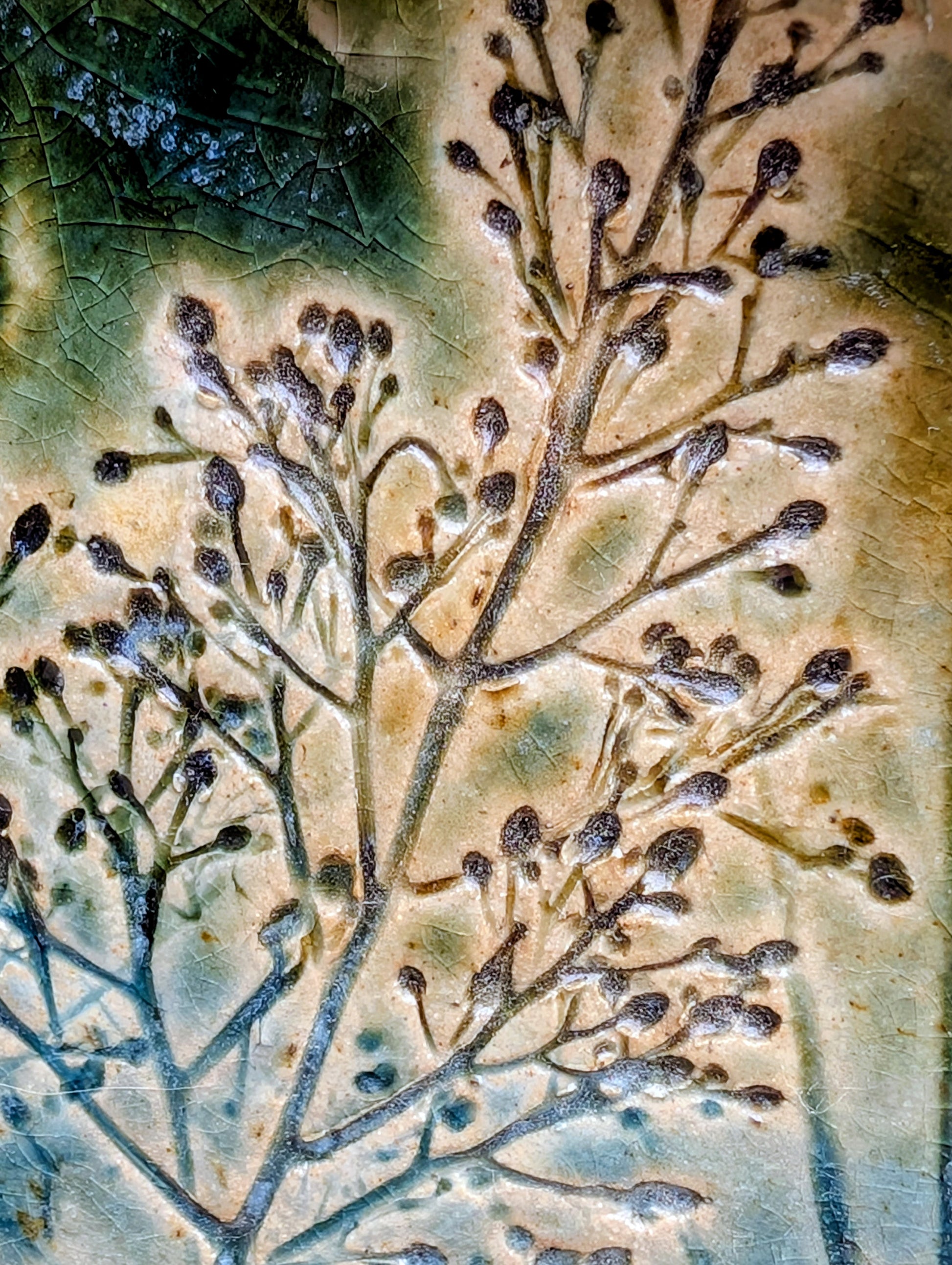 Celebrate the beauty of nature with this signed handbuilt studio pottery platter featuring an elegant botanical relief impressed directly into the clay. Finished in layered blue, teal, and olive glazes, this contemporary stoneware piece is equally at home as functional serveware or displayed as ceramic wall art.