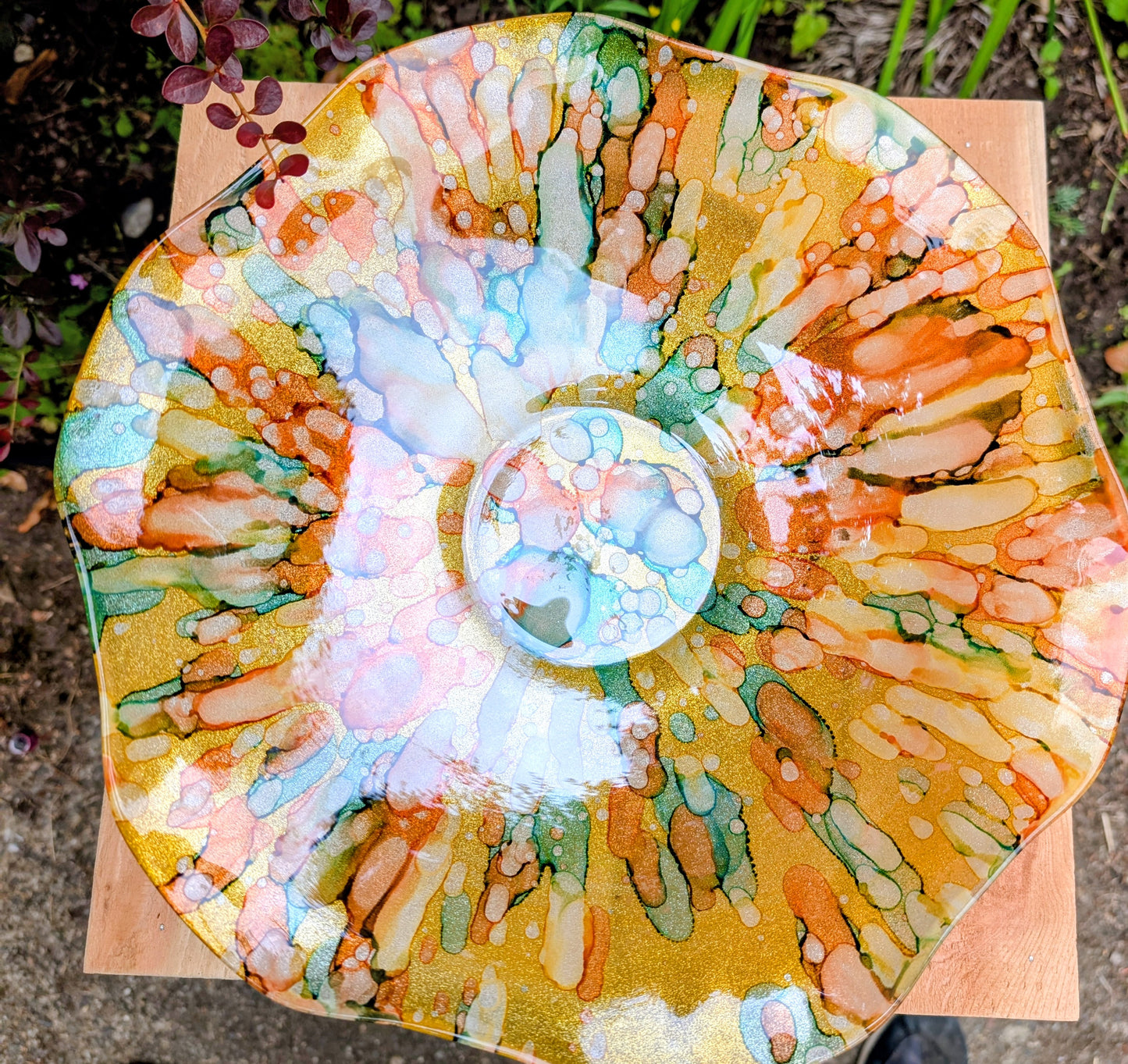 Bring color and light to your home or garden with this contemporary scalloped art glass bowl. Featuring warm golden tones accented by olive green, amber, turquoise, and shimmering metallic highlights, it serves beautifully as a centerpiece, decorative bowl, or tabletop bird bath.