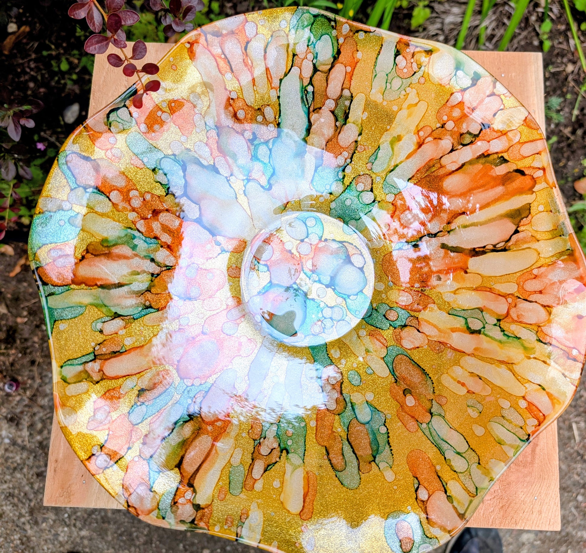 Bring color and light to your home or garden with this contemporary scalloped art glass bowl. Featuring warm golden tones accented by olive green, amber, turquoise, and shimmering metallic highlights, it serves beautifully as a centerpiece, decorative bowl, or tabletop bird bath.