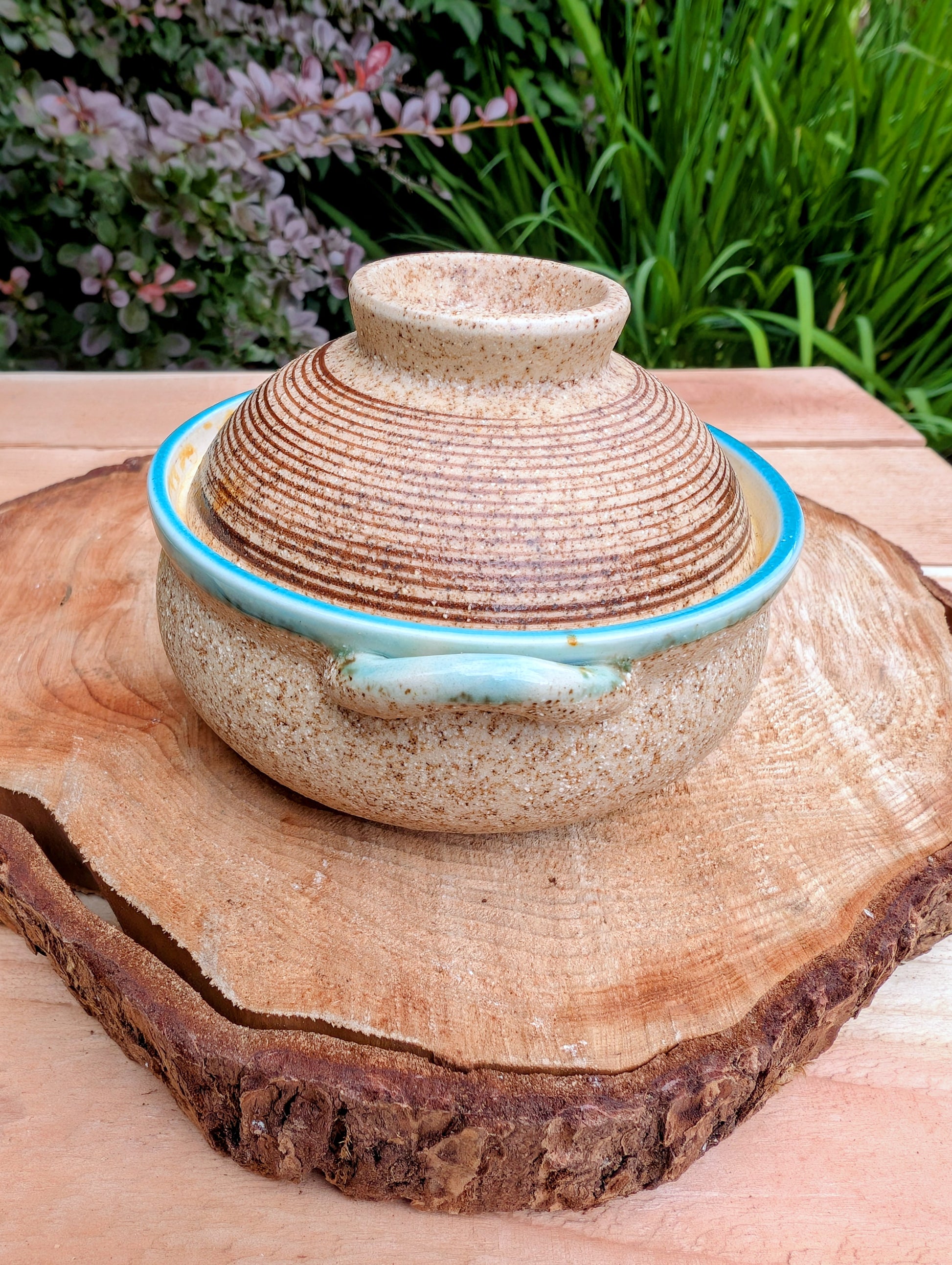 A beautifully handcrafted studio pottery bowl featuring a warm speckled stoneware exterior, vibrant turquoise glazed interior, and matching ribbed lid. Its compact size and organic design make it perfect for serving small dishes or displaying as a timeless piece of artisan pottery.