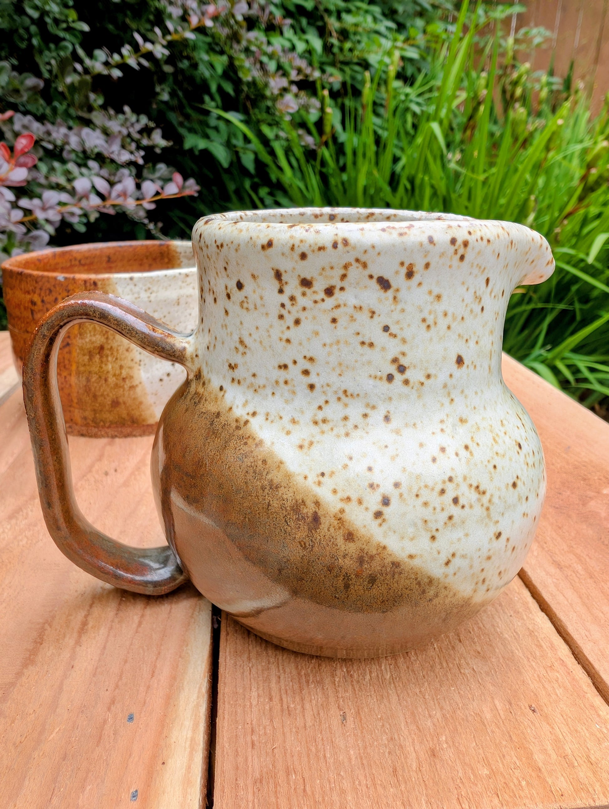 Bring handcrafted warmth to your table with this signed studio pottery creamer and sugar bowl set. Finished in a beautiful speckled cream glaze with flowing olive-brown accents, this artisan stoneware pair blends rustic craftsmanship with timeless everyday function.